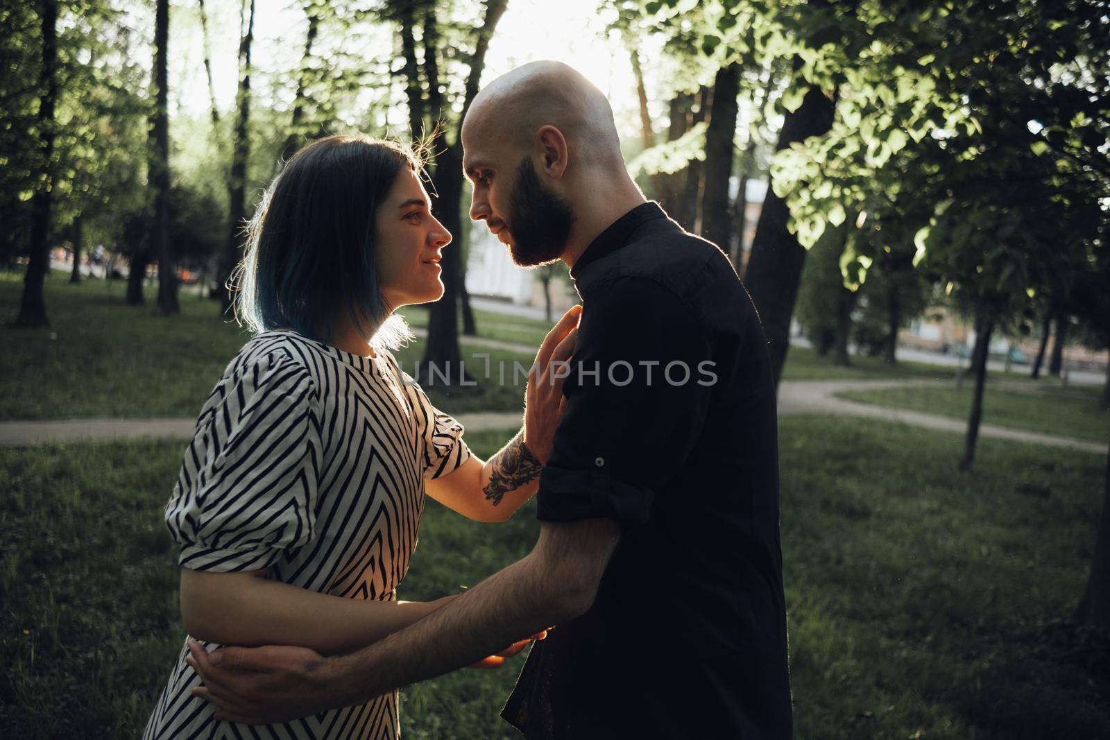 the guy and the girl look at each other and hold hands. in summer in the park. glare of the sun. soft effect by Symonenko