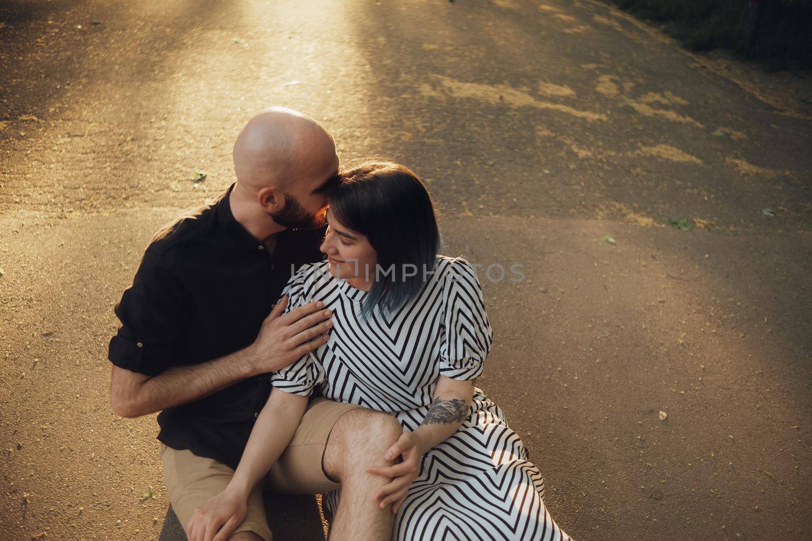 lovers sit in a hug on the asphalt against the background of the sun by Symonenko