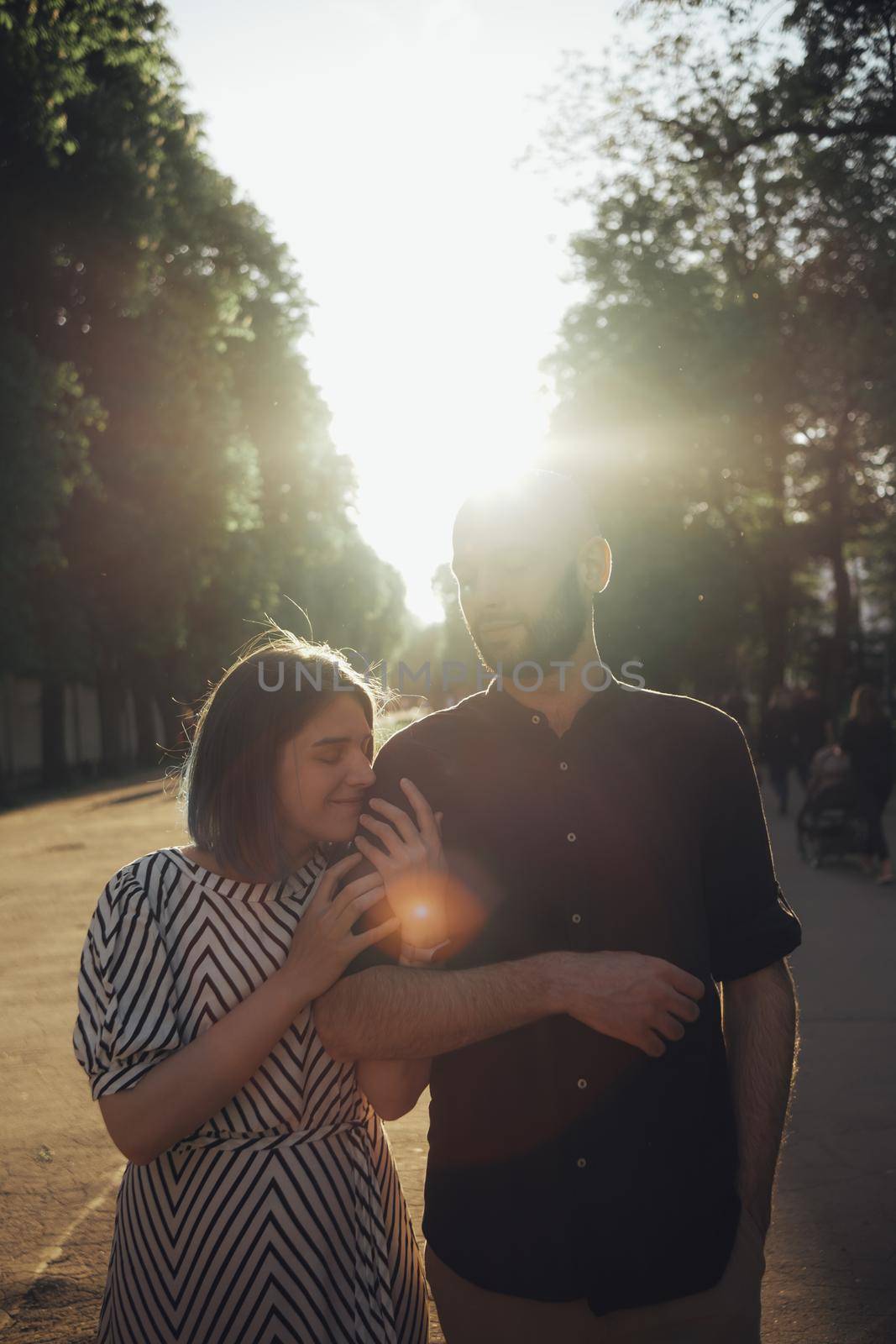 lovers take a walk in the park in the summer. the girl firmly holds the guy's hand. glare of the sun by Symonenko