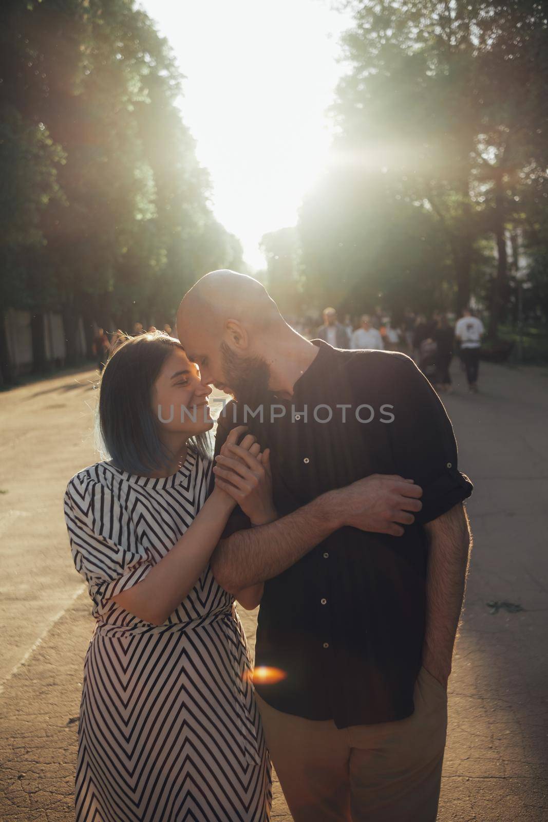 lovers take a walk in the park in the summer. the girl firmly holds the guy's hand. glare of the sun by Symonenko