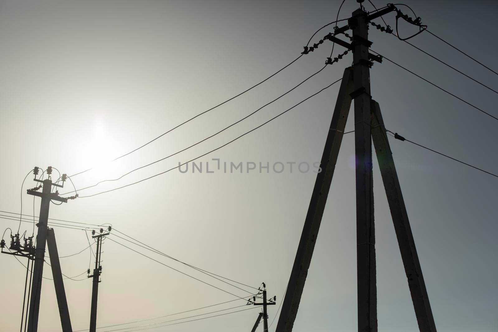 Poles with electrical wires. Silhouettes of communication racks. High voltage lines. Energy transfer. Concrete electric poles.