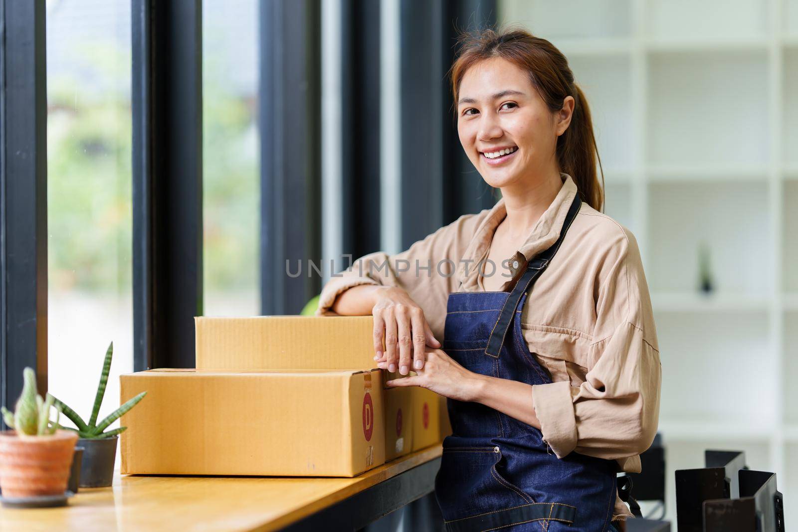 A portrait of Asian woman, e-commerce employee freelance with parcel box for deliver to customer. Online marketing packing box delivery concept