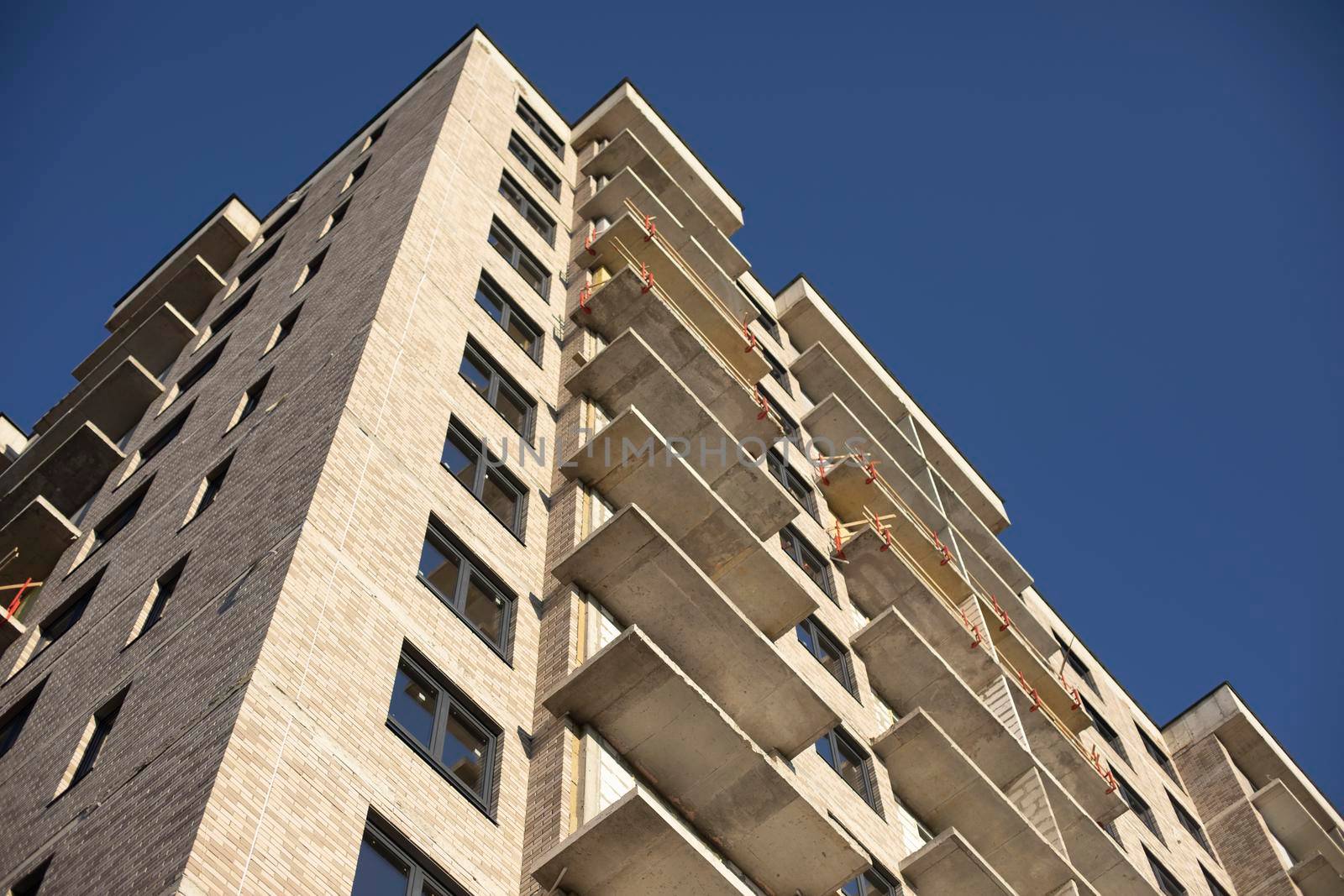 Facade of building. Unfinished house. Windows in new multi-storey building. Plastic windows on street. by OlegKopyov