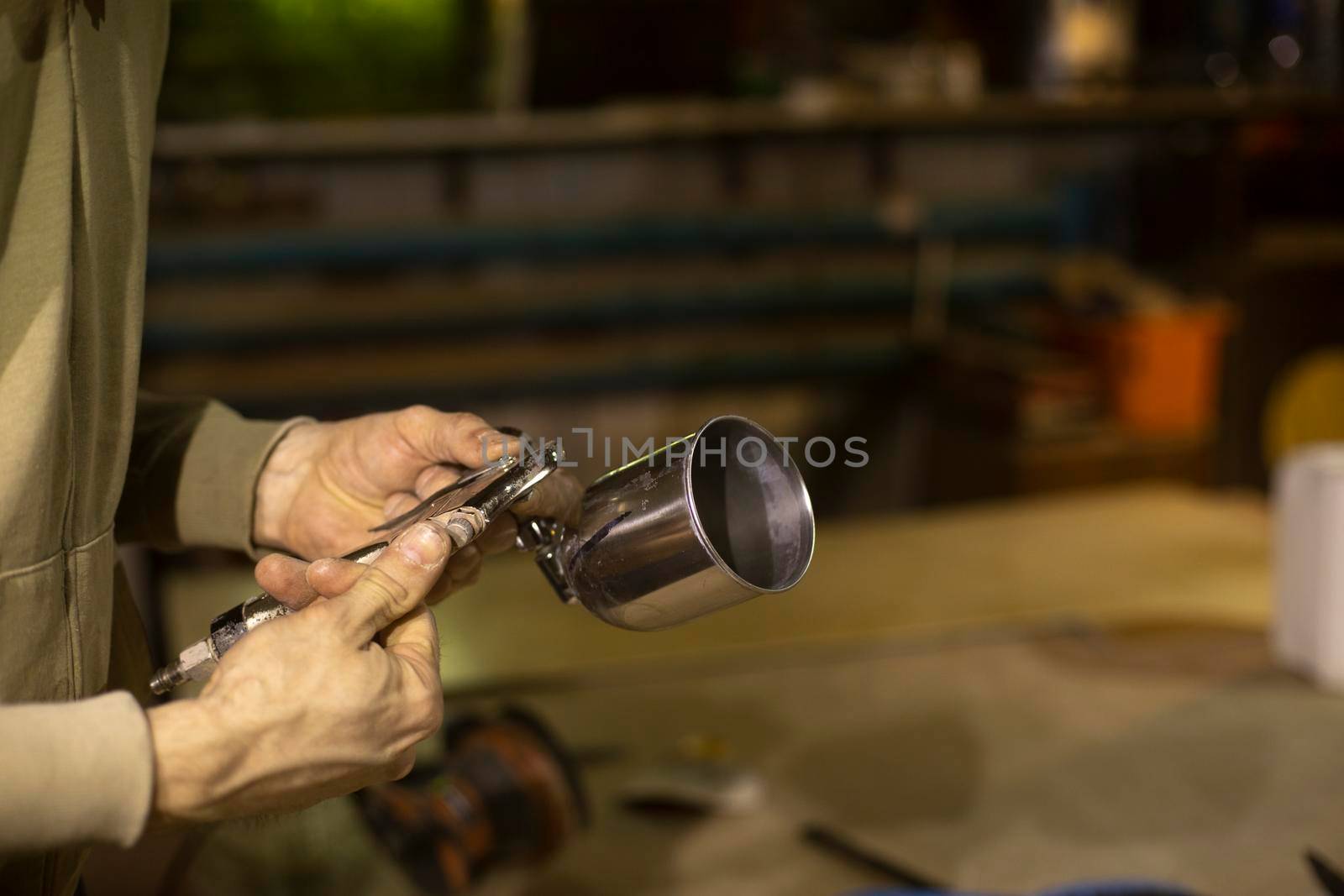 Guy is holding airbrush. Man with painted remote in his hand. Tool details in garage.