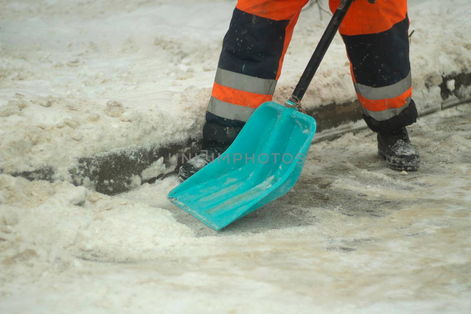 Cleans snow with a shovel. Workers are cleaning the roads after a snowfall. Snow drift. Communal services are putting things in order.