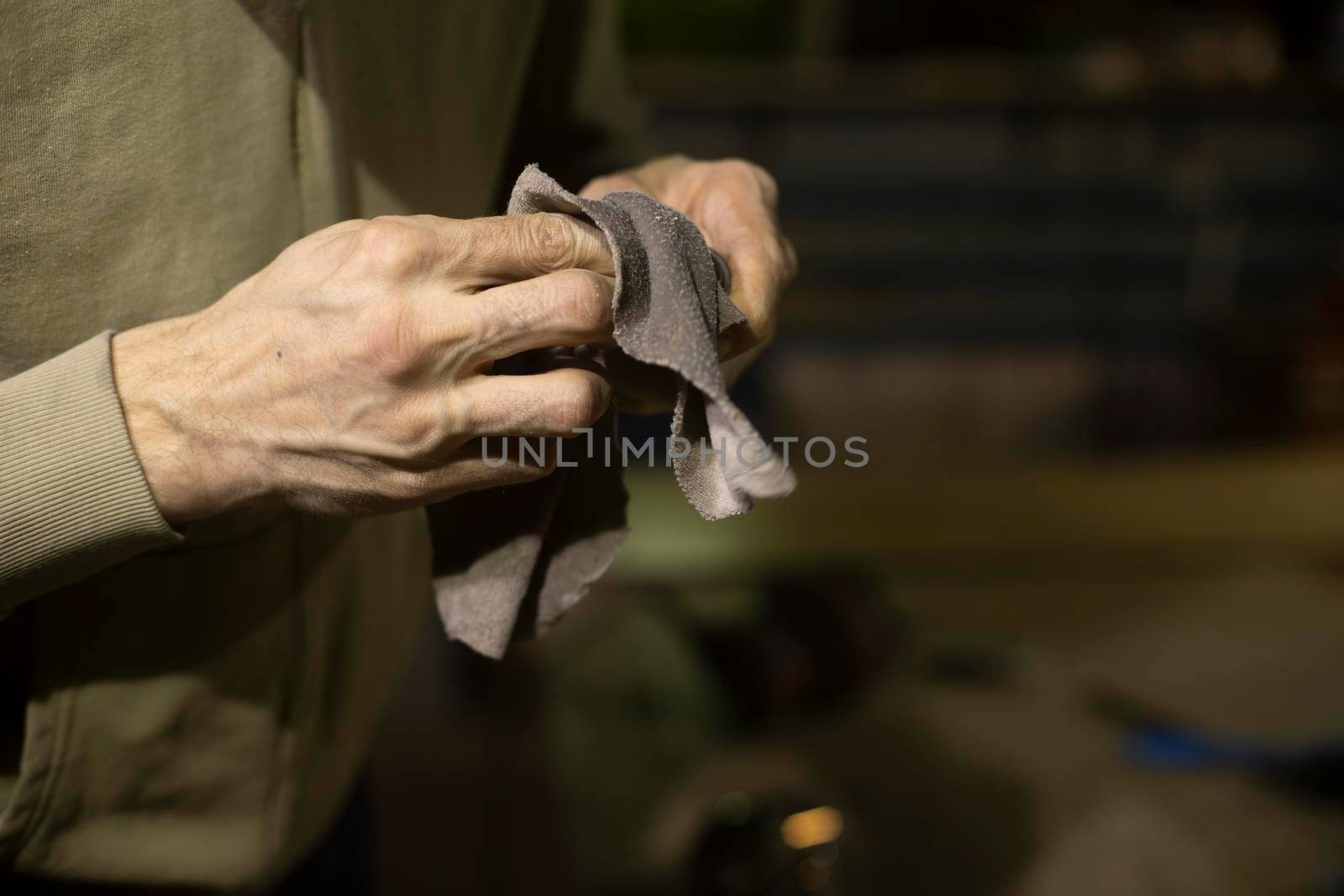 Wipe part with rag. Rag in his hands. Person cleans mechanism from dirt. Hands of man.