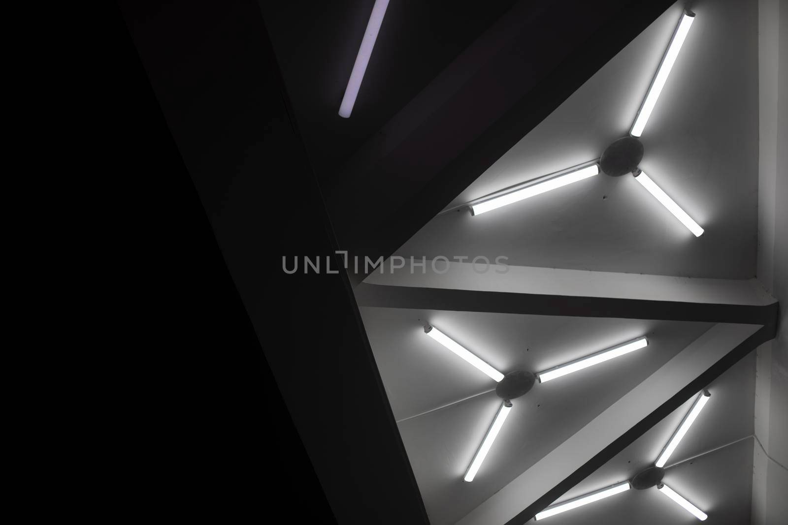 Light design. Fluorescent lamps on ceiling. Triangles of lamps. Interior details. Architecture of 20th century.