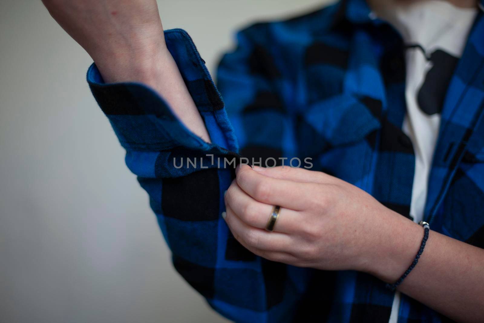 Girl fastens buttons on her shirt. Cozy plaid shirt. Clothes for home. Woman thinks what to wear. Household details. Blue shirt. Man's clothes on student.