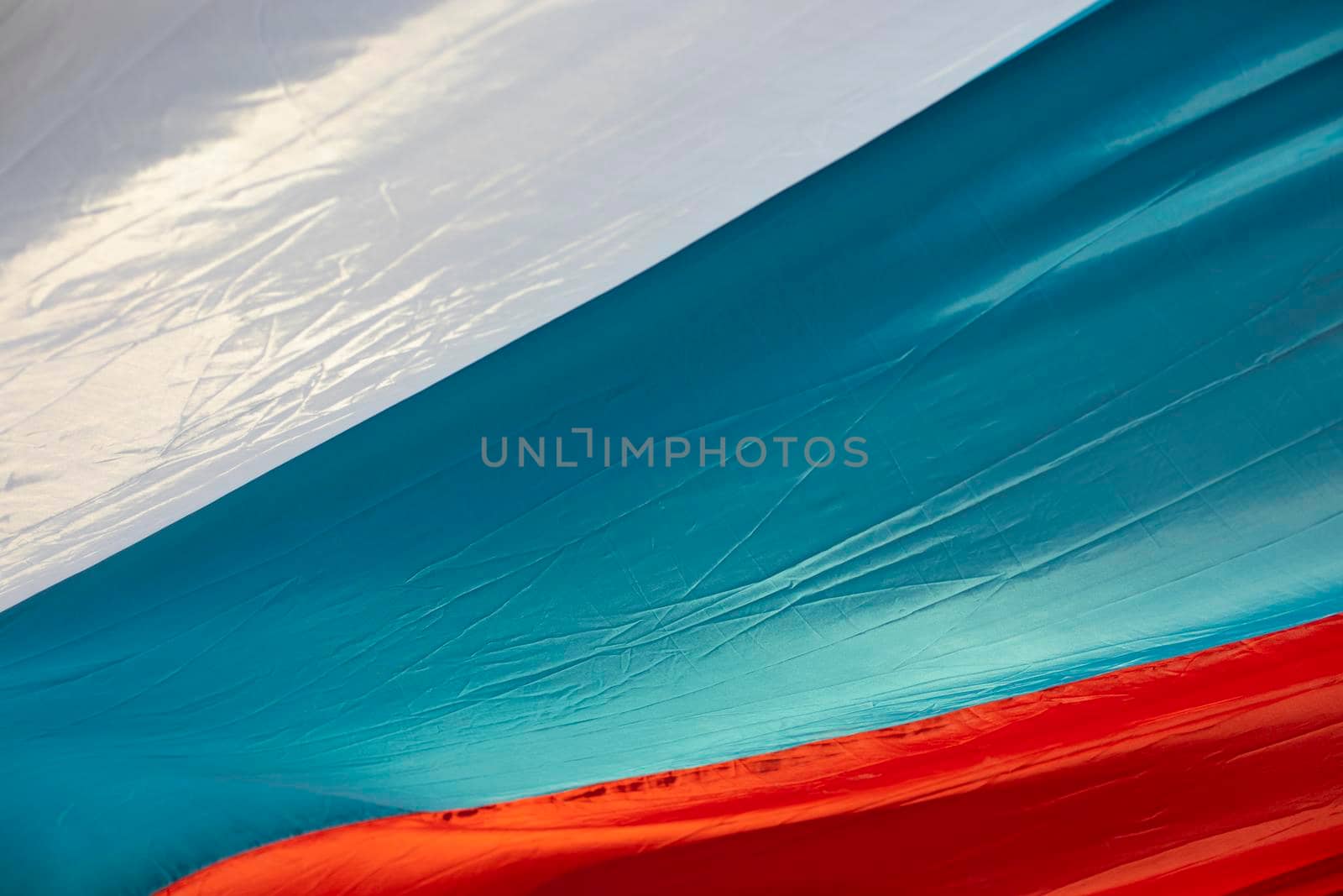 Flag of Russia. Fabric is white, blue and red. Flag in wind. Folds on fabric. Texture of national flag.