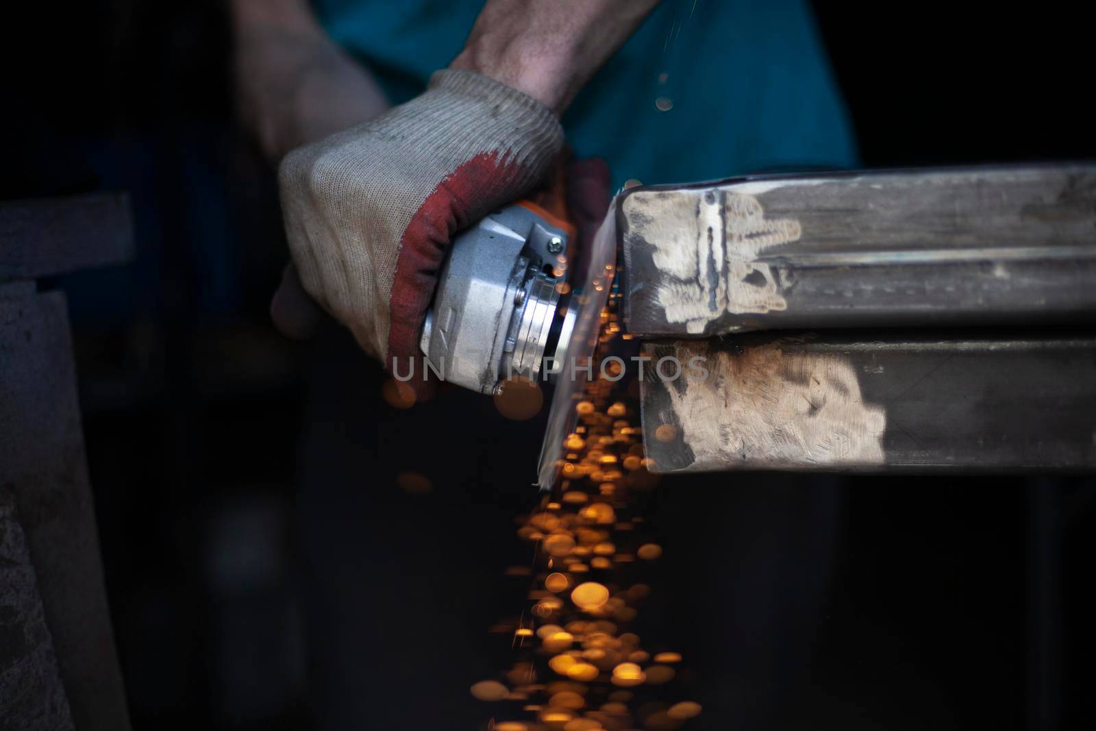 Metal cutting. Grinding steel. Work as a grinder. Sparks from friction. Men's work. Creating a design. The project in the workshop. Iron processing. Hand electric tool.