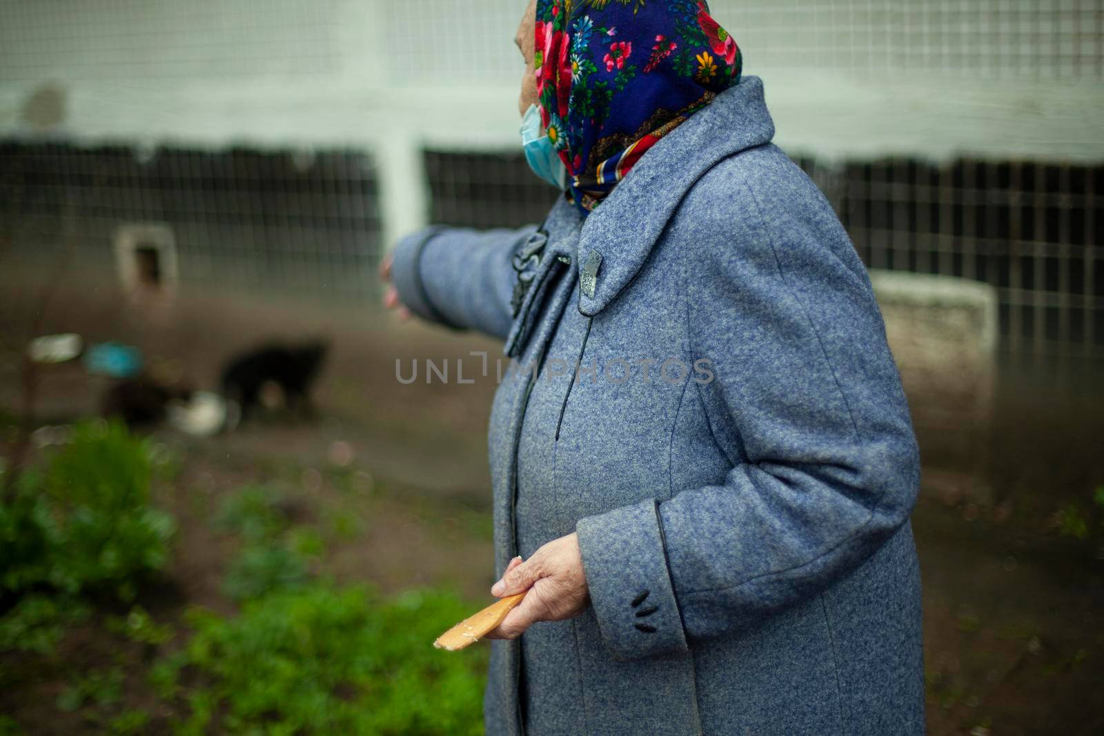 An old woman in Russia. Pensioner in a coat on the street. by OlegKopyov