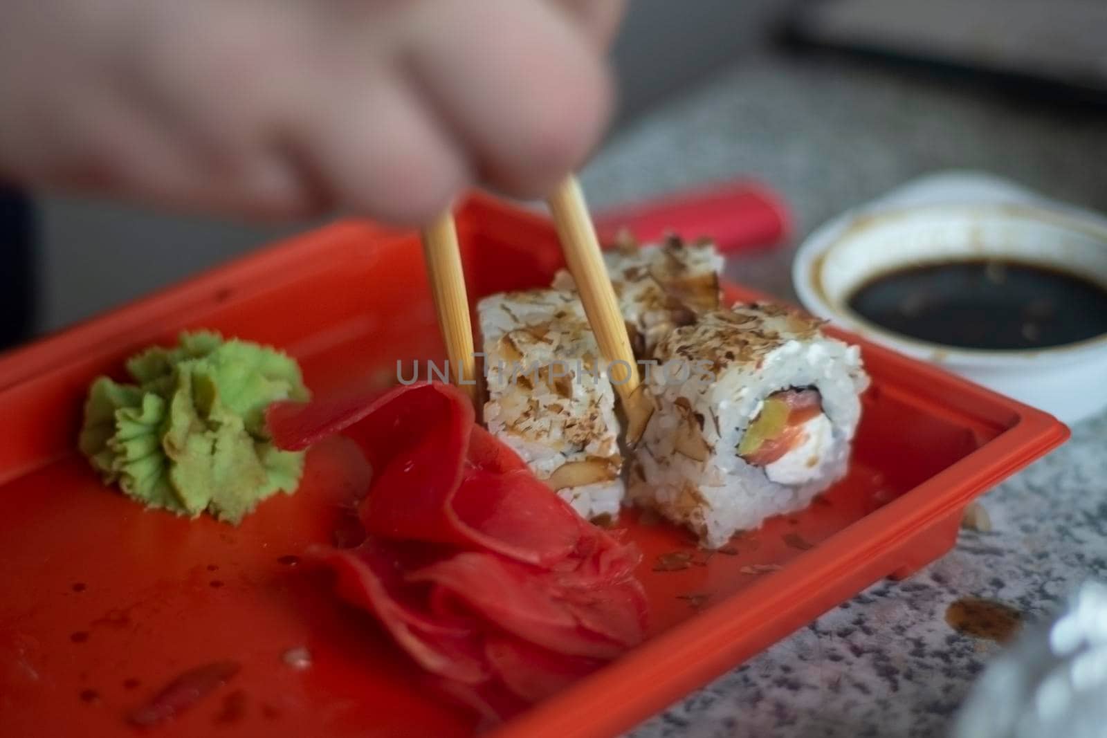 Sushi with fish and rice. Food from restaurant. Takes sushi with wooden sticks. Food from Chinese restaurant. Oriental cuisine. Delivery of lunch to house. by OlegKopyov