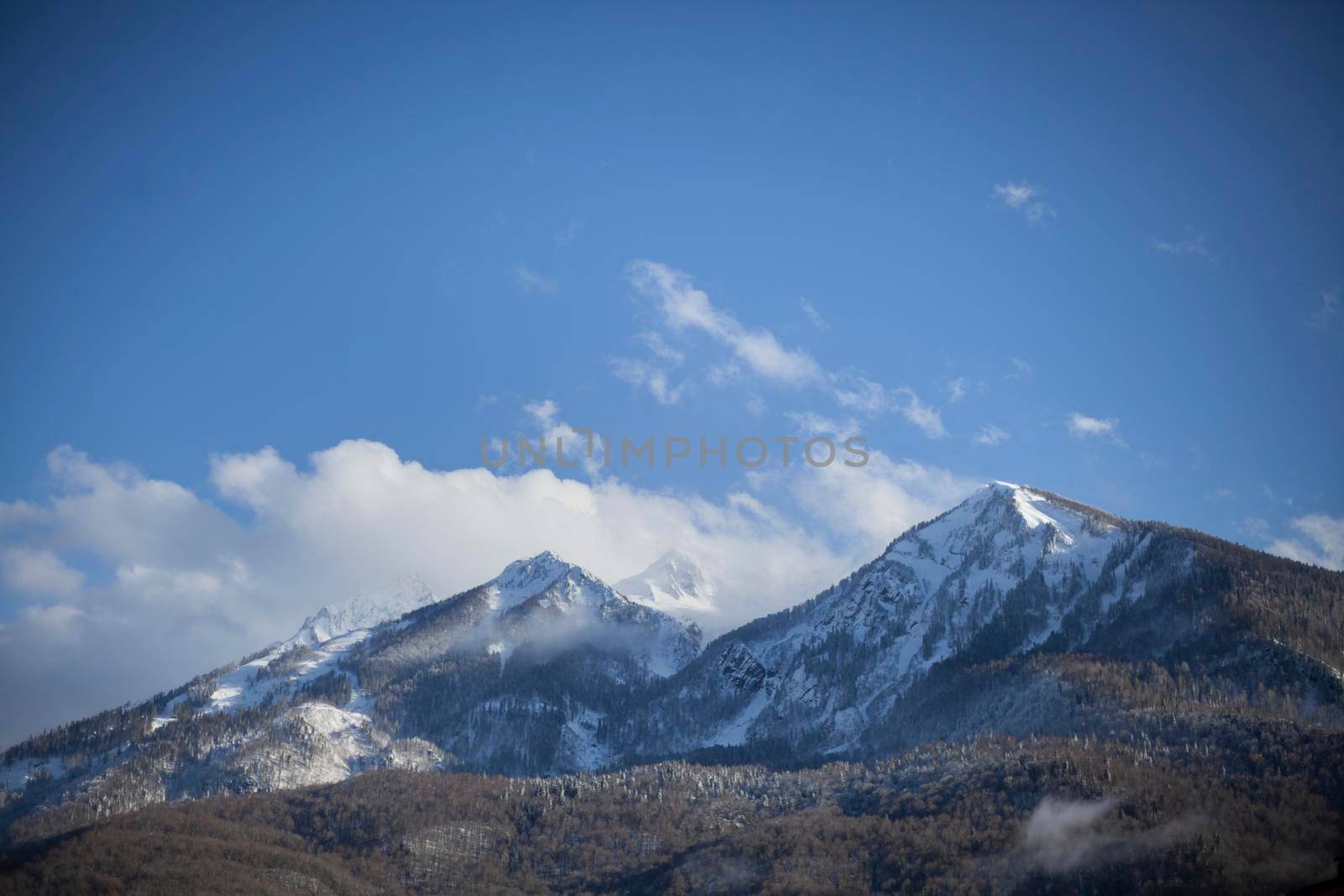Mountain landscape in early spring. The fog slides from the mountains. Snow peaks. Ski resort. Beautiful highland background. Wide view of the mountain range. The calm of northern nature.