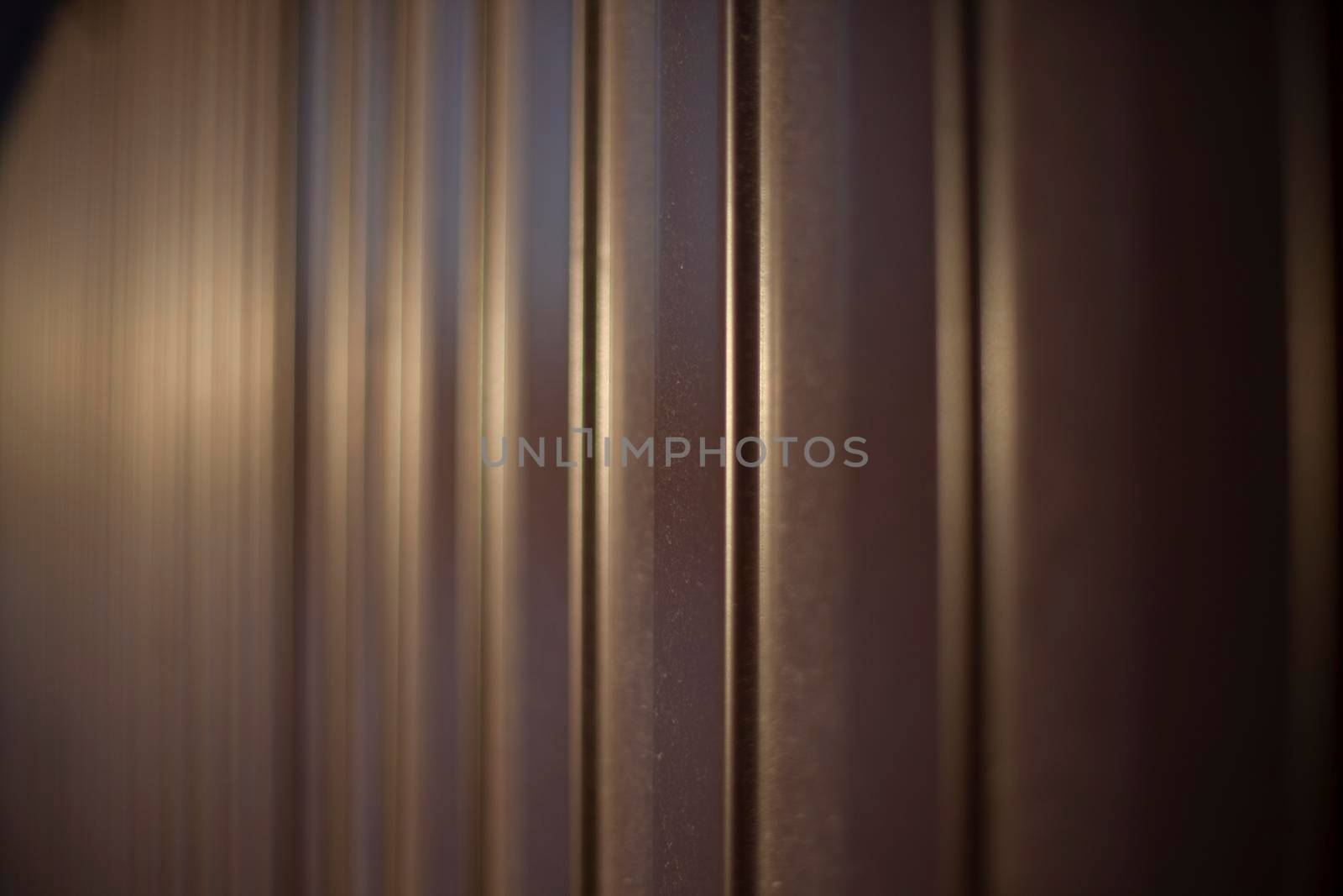 Texture of steel fence. Profile sheet is brown. Fence details. Blurry background in sunlight.