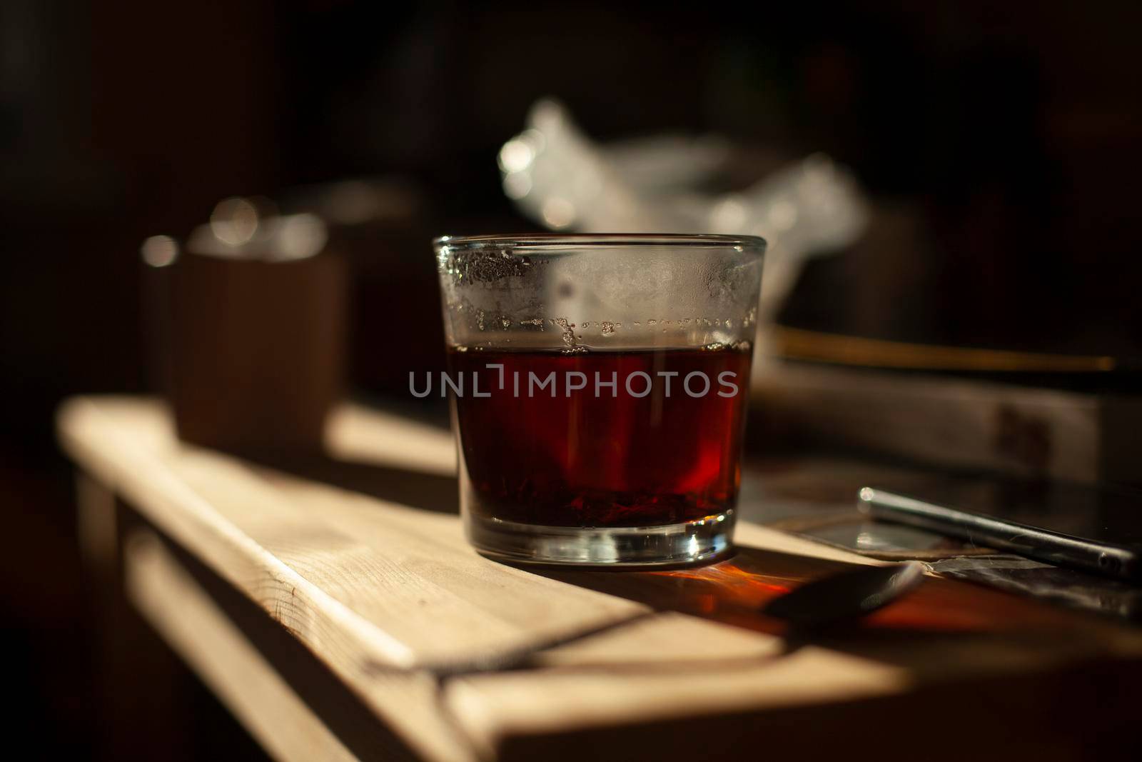 Tea in glass. Kitchen details. Hot drink in morning. Strong black tea. Transparent cup.