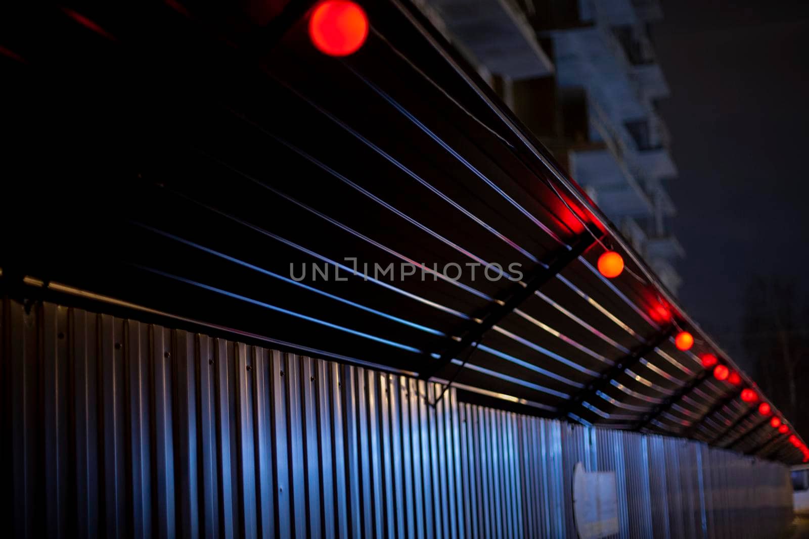 Fence at night. Fencing of territory. Barrier is made of metal profile. Texture of stainless steel. by OlegKopyov