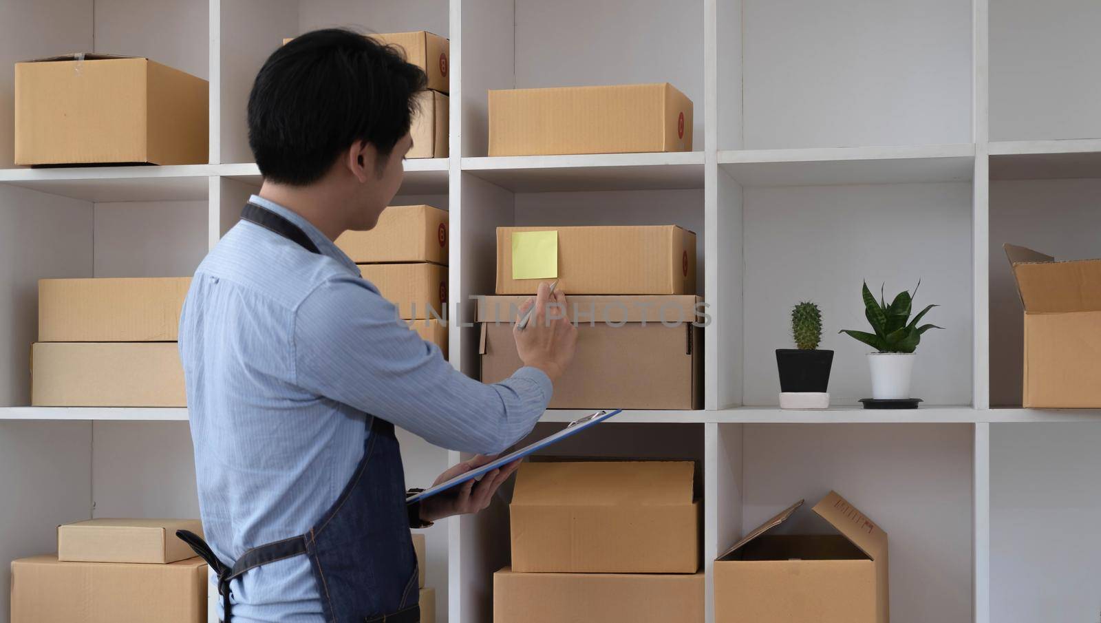 The seller Asian young man prepares the delivery box for the customer by wichayada