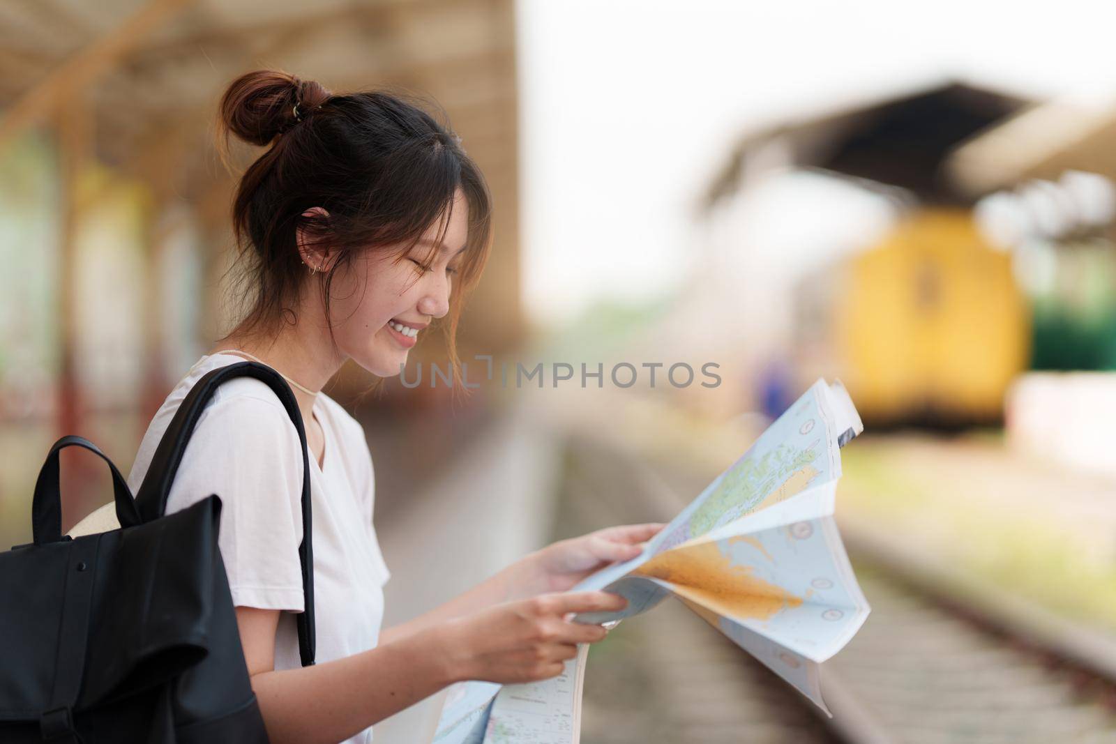 Young traveler woman looking on maps planning trip at train station. Summer and travel lifestyle concept