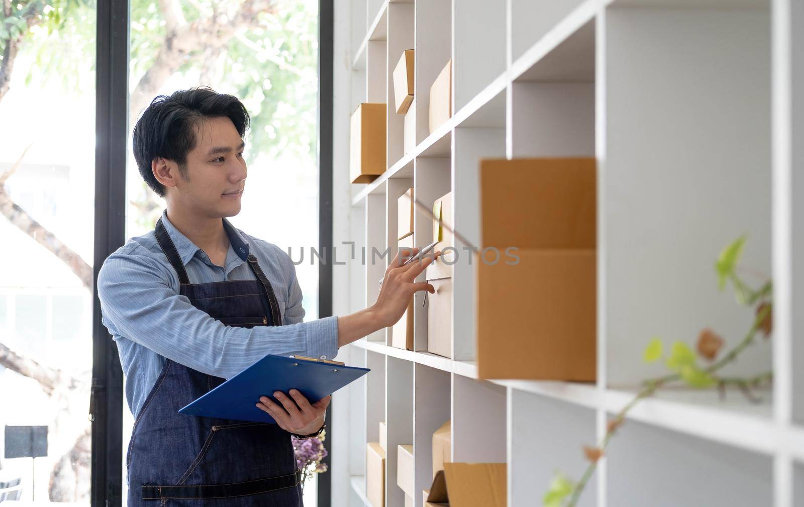 The seller Asian young man prepares the delivery box for the customer by wichayada