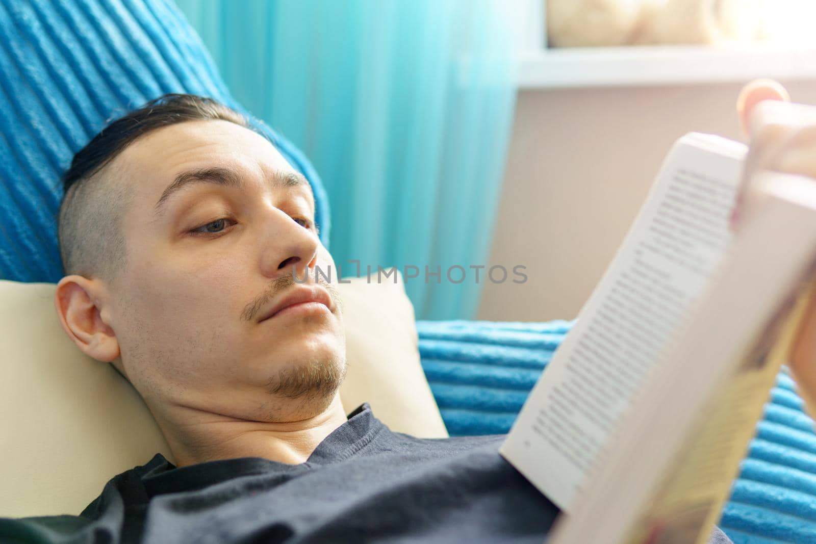 Leisure, education, literature and home concept close up of man lying on couch and reading book at home by darksoul72