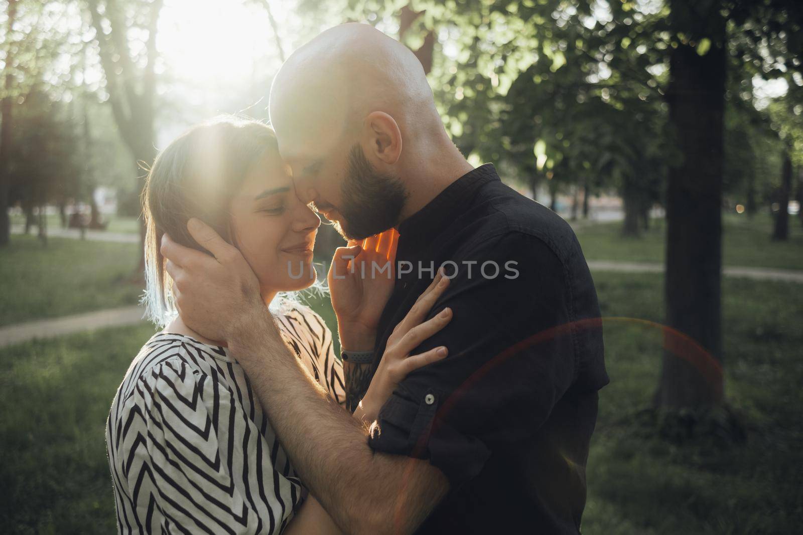 a guy strokes his face and is about to kiss his girlfriend standing in the summer sun. glare of the sun. soft effect by Symonenko