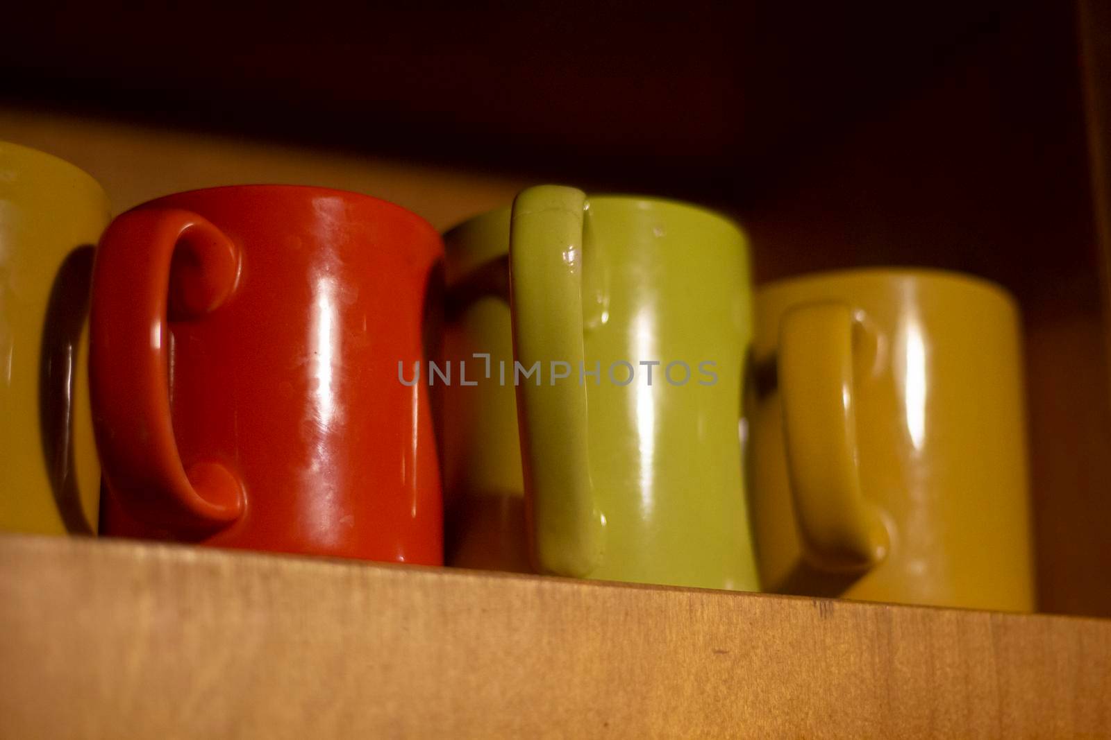 Cups on shelf. Colorful glasses for drinks. Utensils in kitchen. Containers for liquids. Interior details. by OlegKopyov