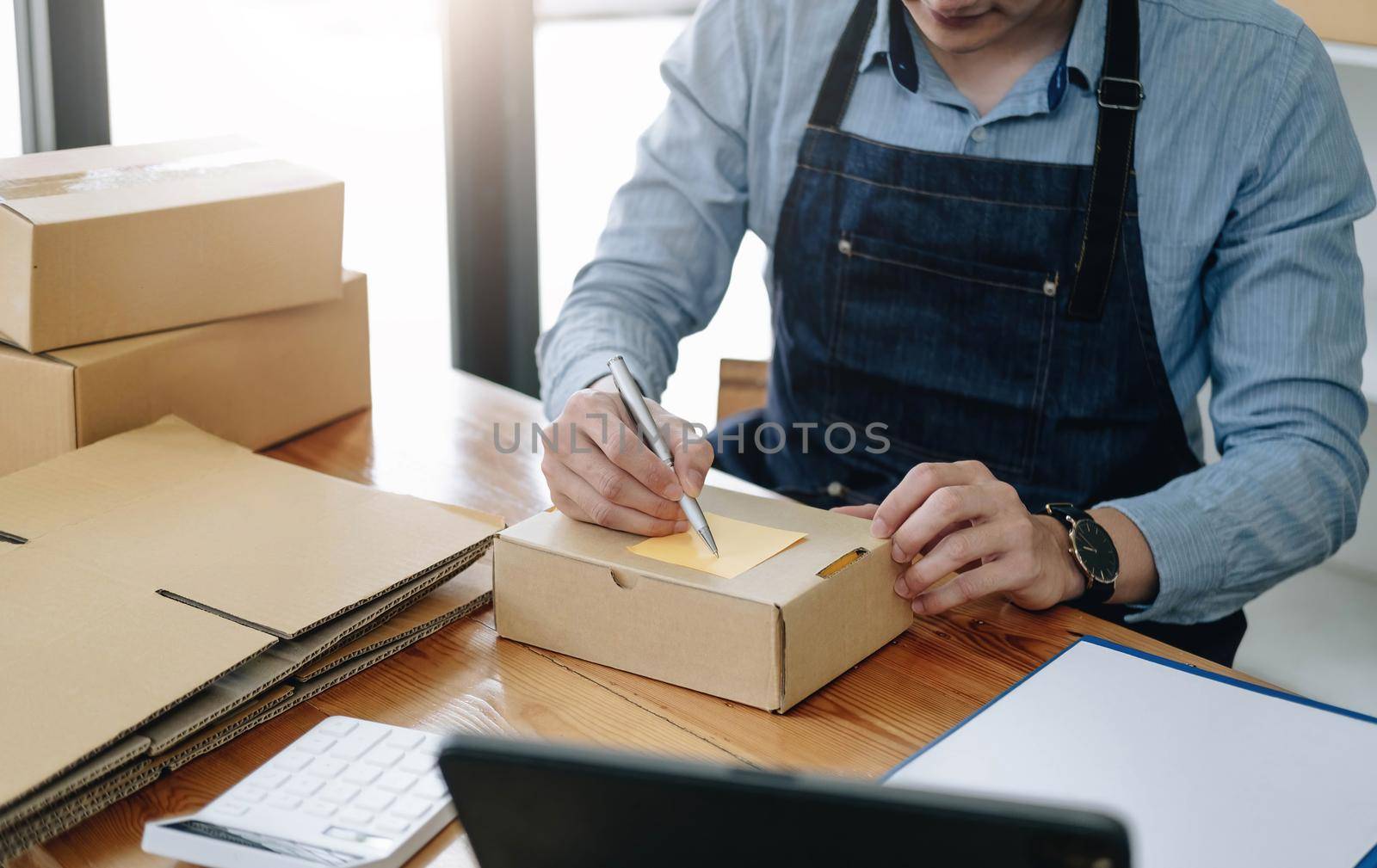 The seller Asian young man prepares the delivery box for the customer by wichayada