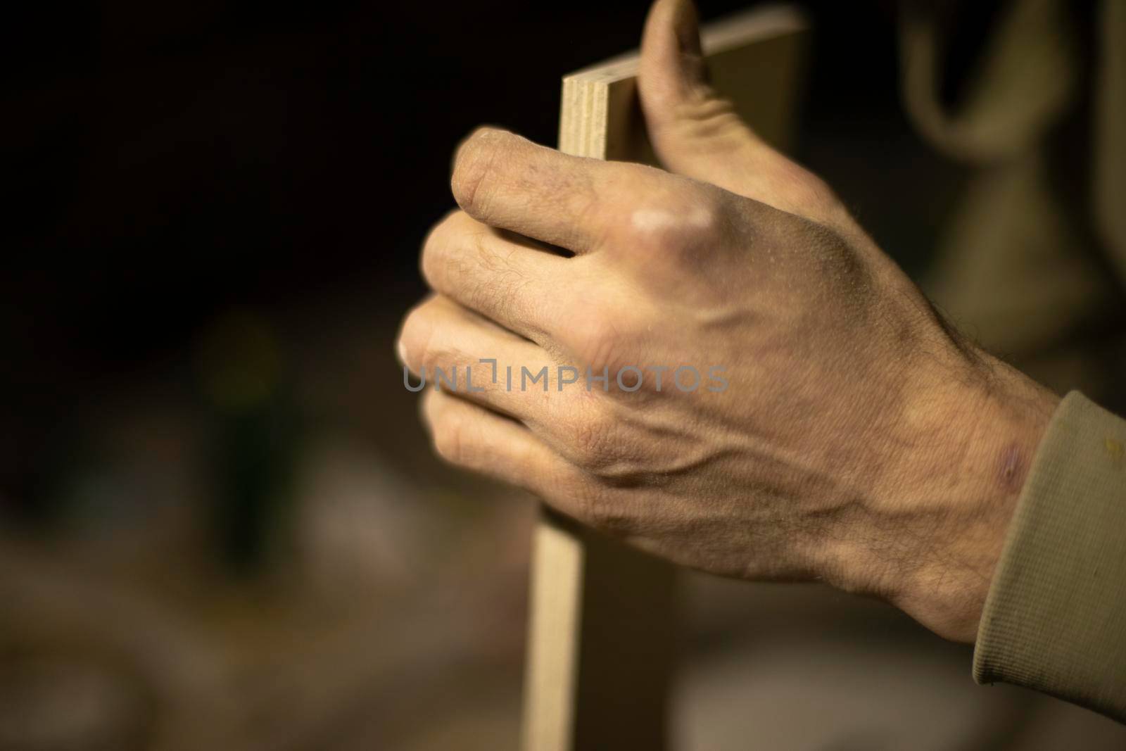 Carpenter holds tree. Worker chooses board. Details of carpentry workshop. Hand of woodworking master.