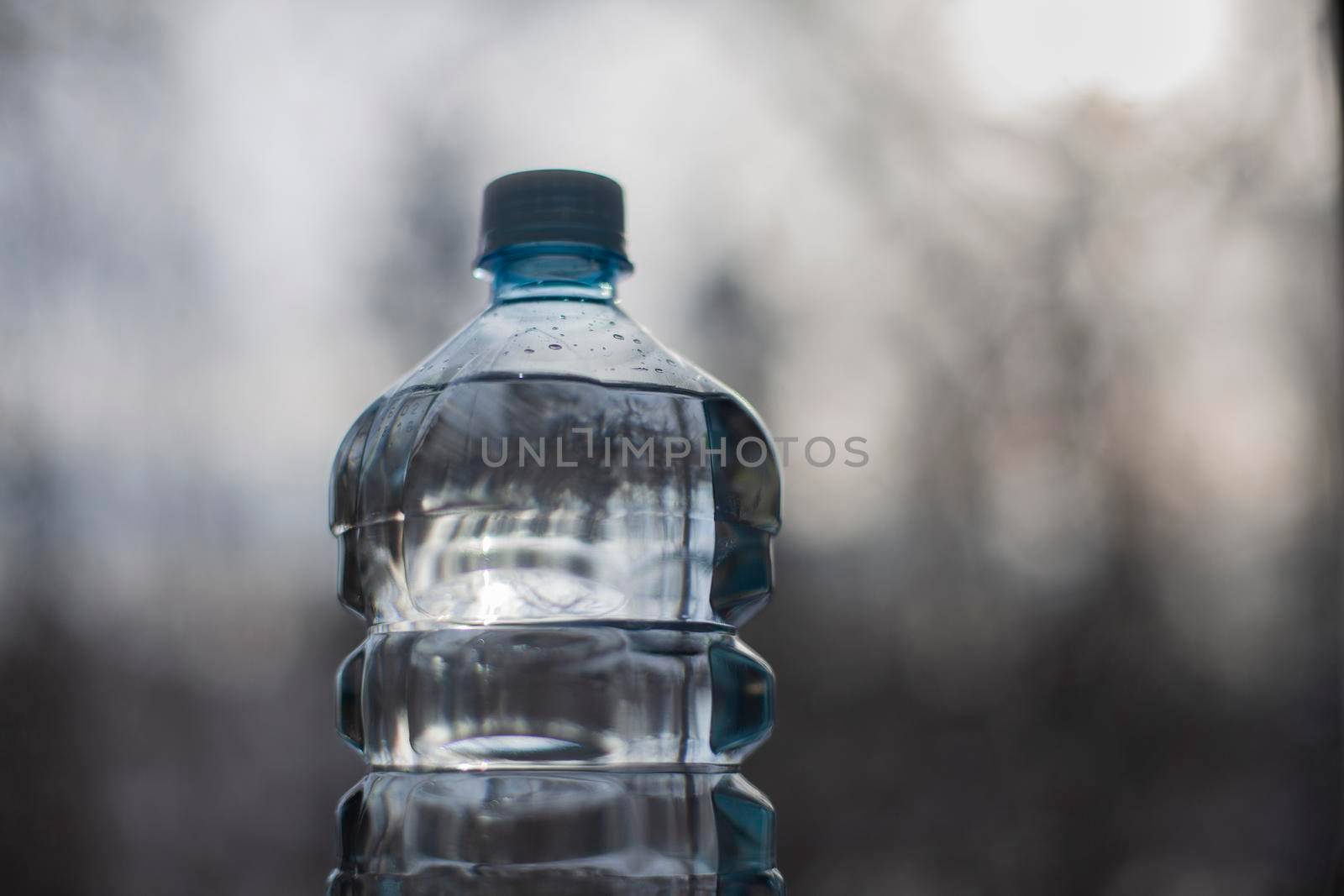 Water bottle. Clean water in plastic bottle. Clear liquid. Background reflection in surface of water.