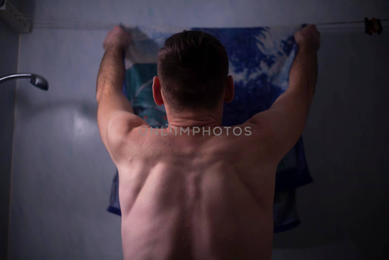 The guy dries a towel in the bathroom. Young man with a bare back. Body cleanliness. Tall man doing household chores. by OlegKopyov