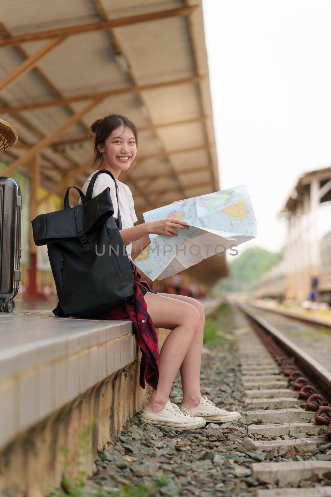 Young traveler woman looking on maps planning trip at train station. Summer and travel lifestyle concept