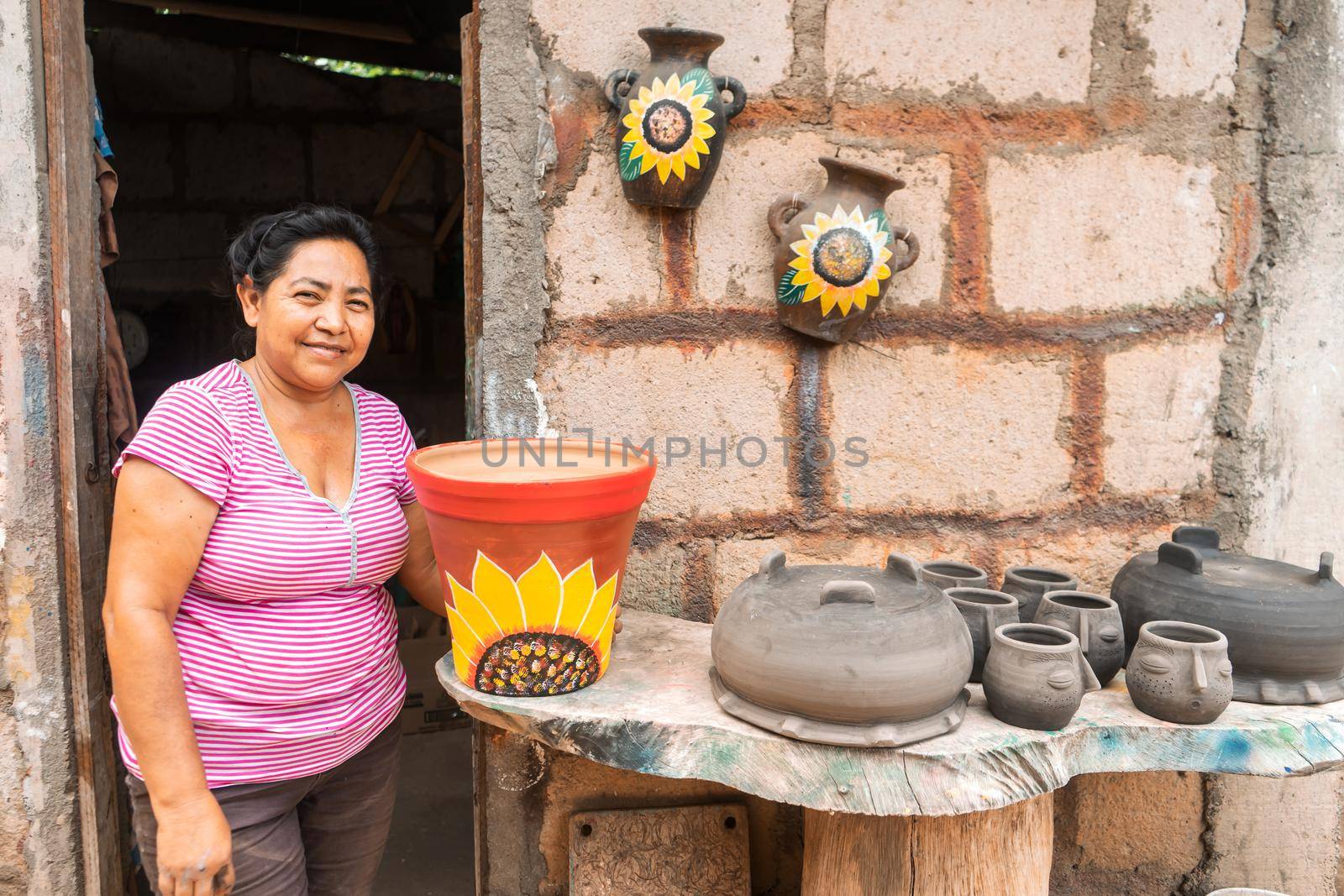 Artisan woman from La Paz Centro Nicaragua posing next to her clay crafts and smiling watching the camera