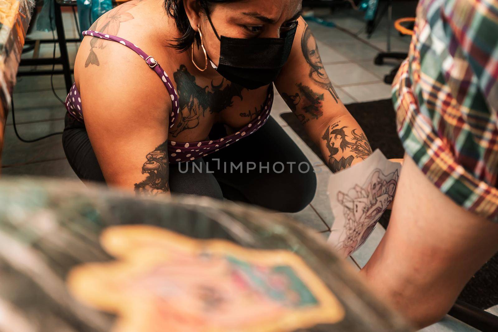 Latina tattoo artist putting a sketch of a tattoo on her client's leg in a studio in Managua, Nicaragua.