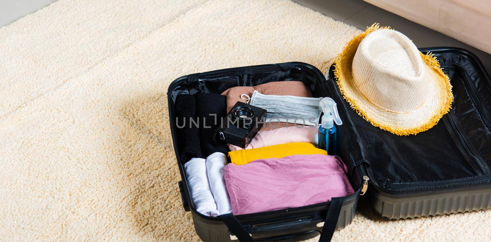 Open suitcase with traveler belongings clothes and accessories of things ready packing to be taken on summer holiday by Sorapop