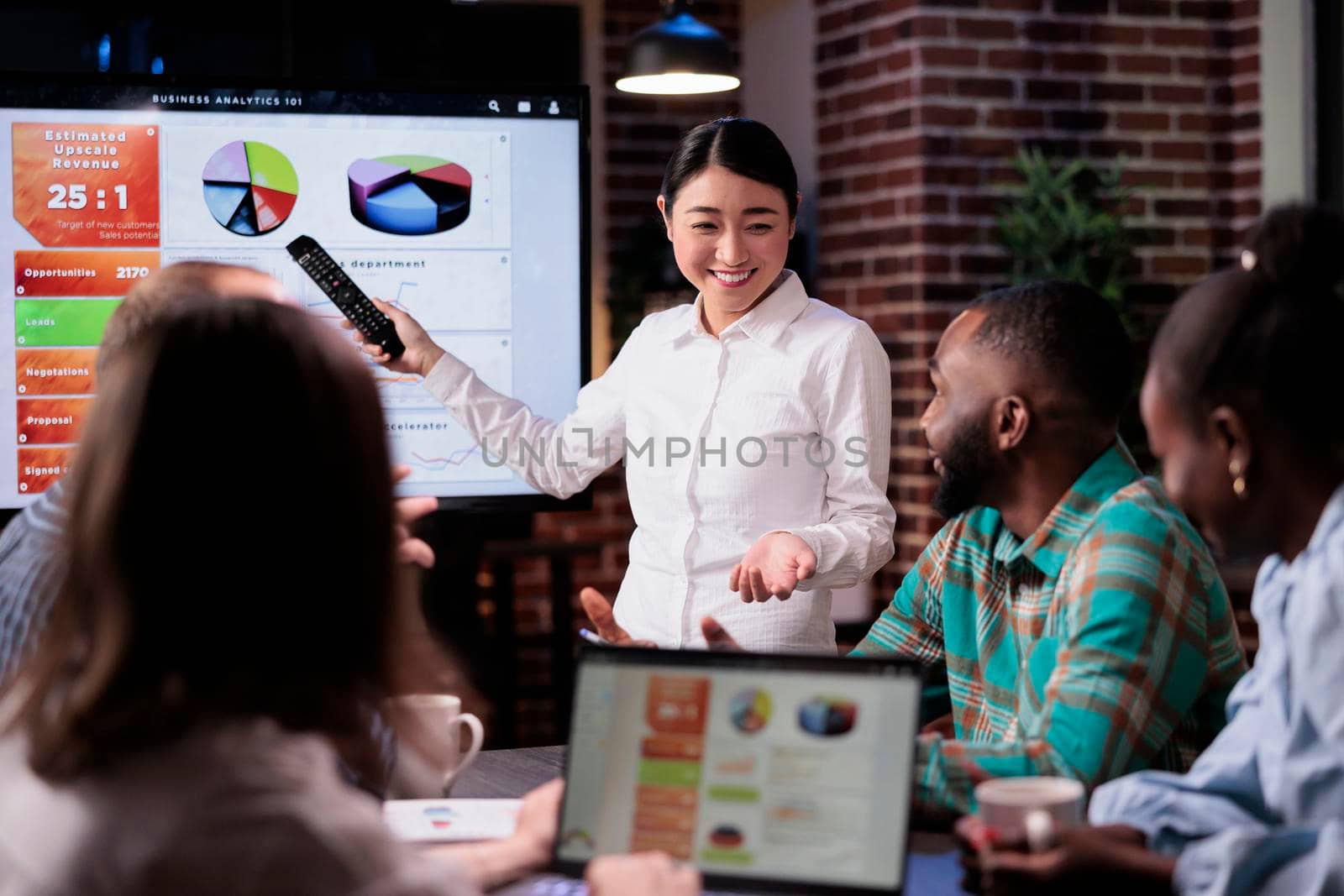 Asian business woman happy with startup company turnover smiling at coworkers in late night meeting by DCStudio