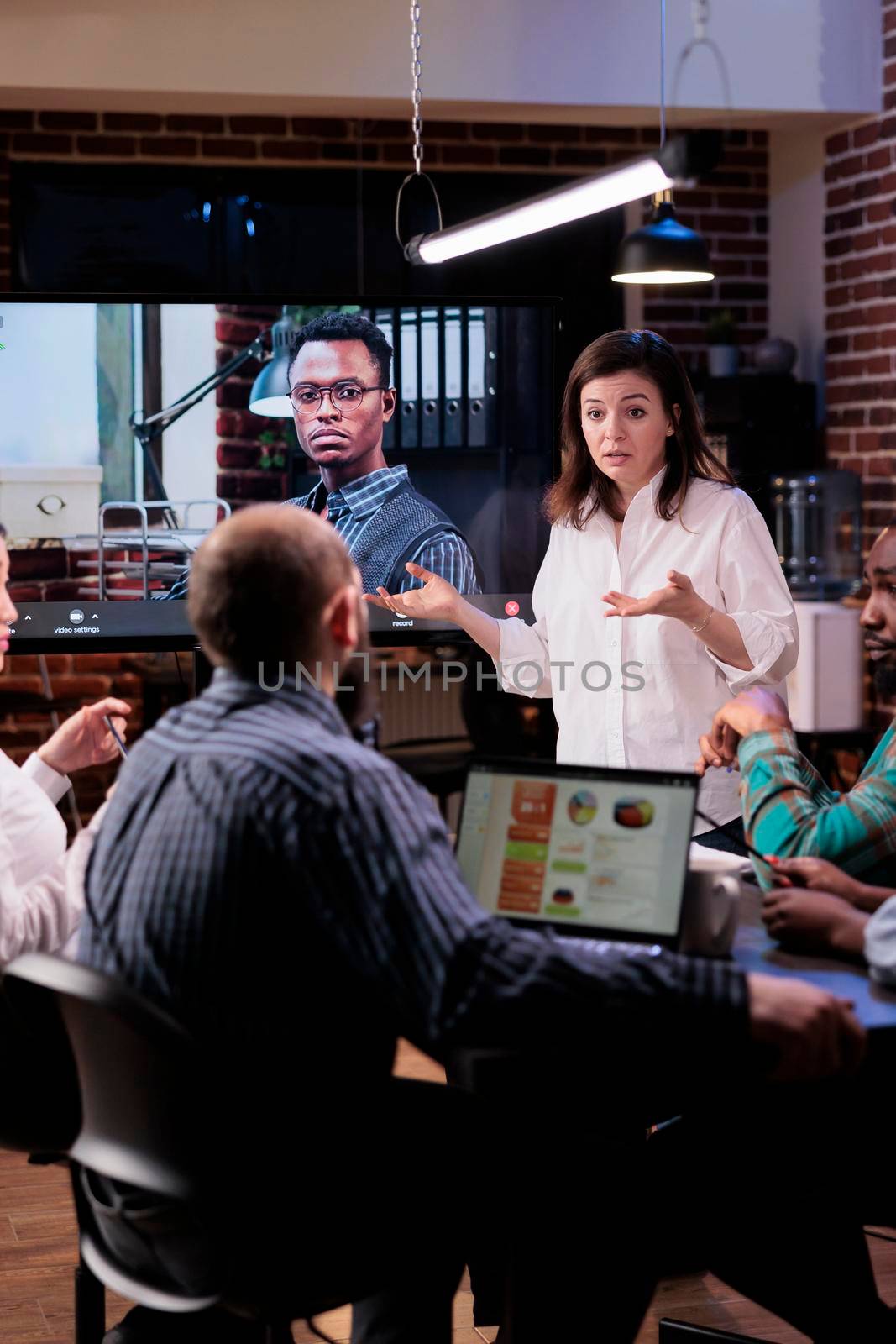Confused startup woman talking during online video conference in late night meeting feeling tired by DCStudio
