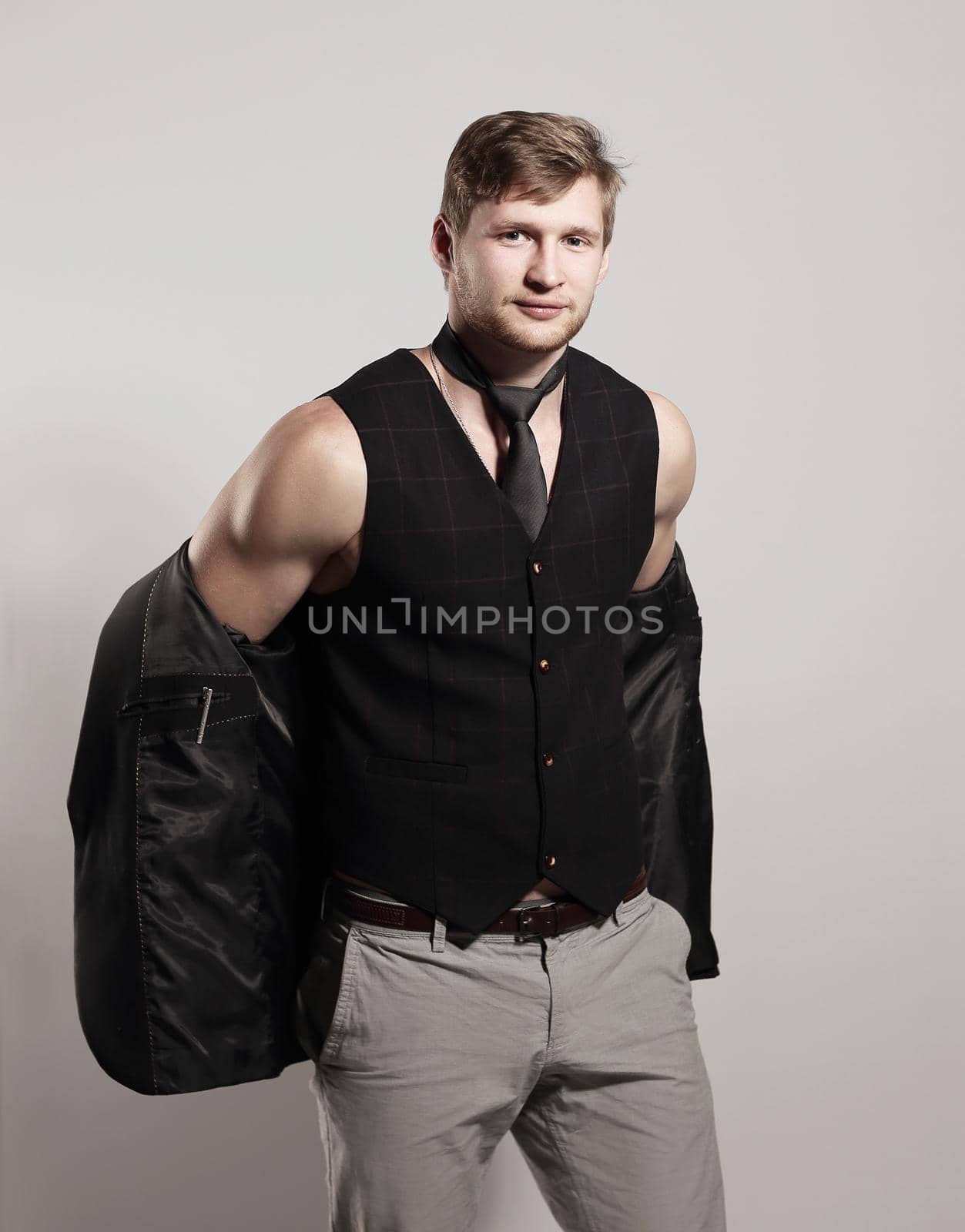 young businessman in a business suit without a shirt holds a jacket over his shoulder by SmartPhotoLab