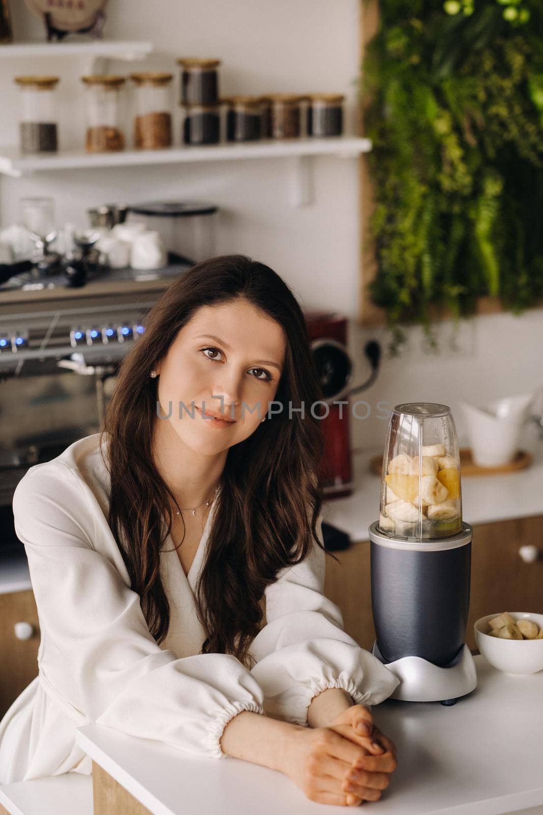 Portrait of a girl who makes a delicious fruit cocktail in the kitchen. Diet for weight loss.