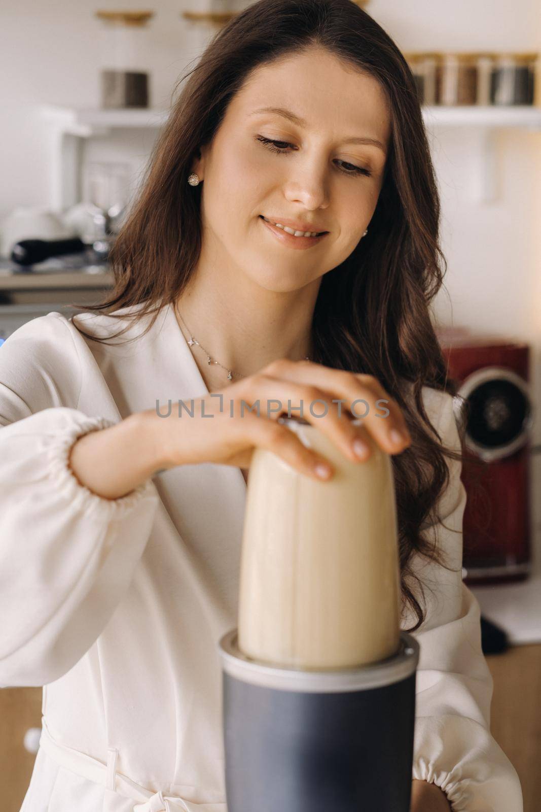 a girl makes a cocktail in a fruit blender in the kitchen. Diet for weight loss.