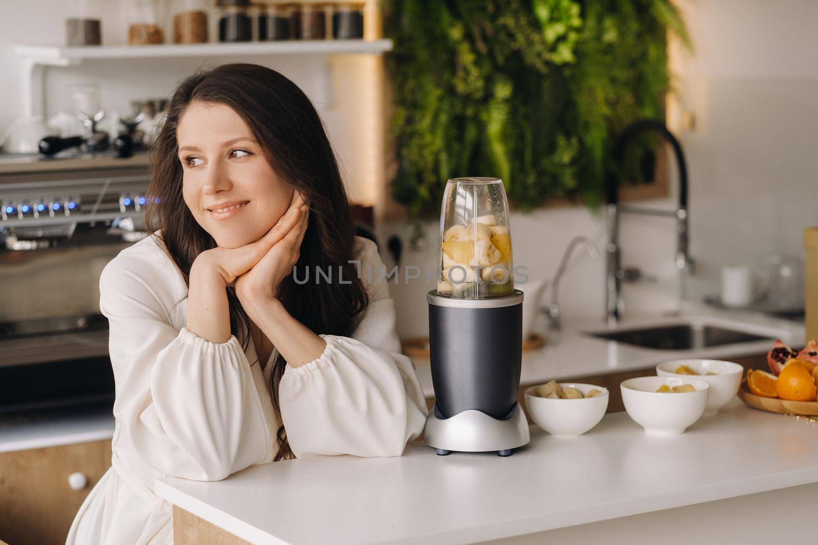 Portrait of a girl who makes a delicious fruit cocktail in the kitchen. Diet for weight loss.