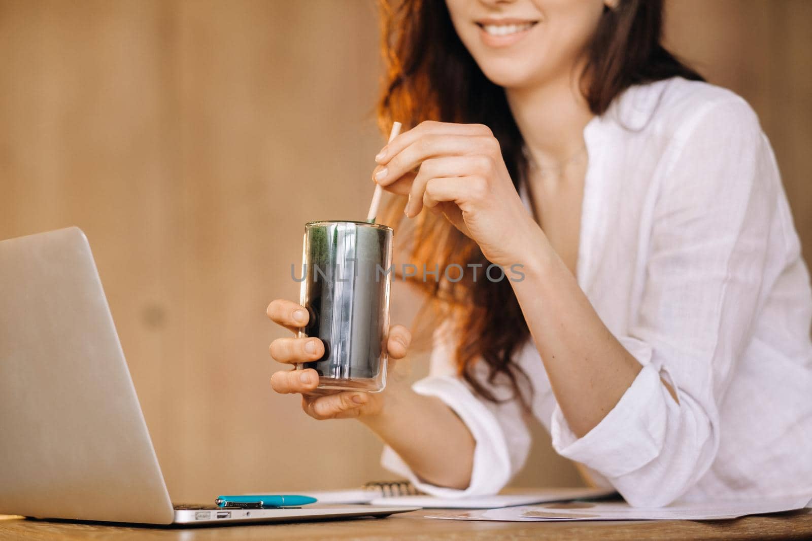 A young freelance woman with a cocktail in her hands at her workplace at work.