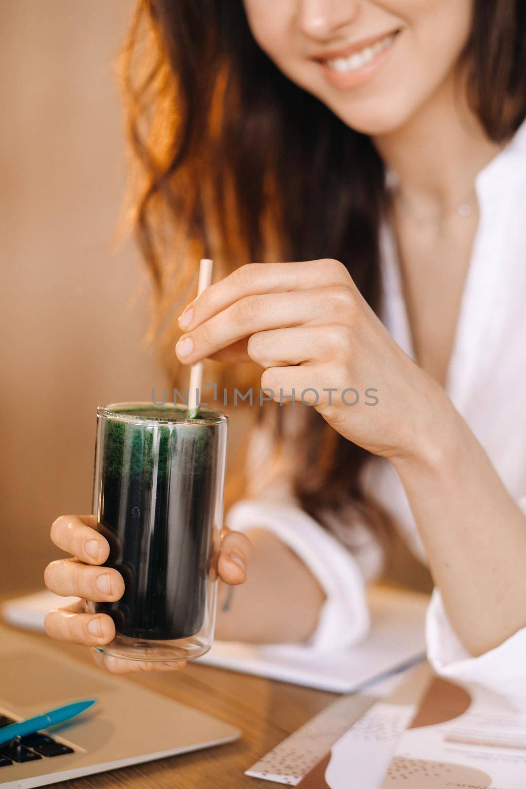 A young freelance woman with a cocktail in her hands at her workplace at work.