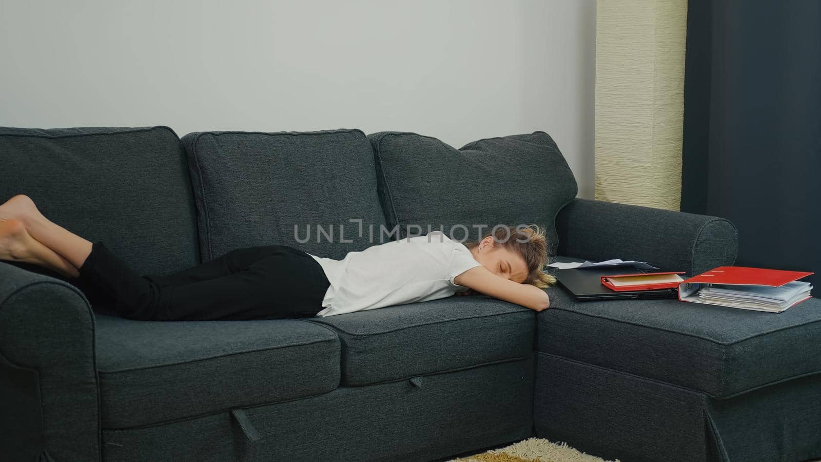 First work experience. The young woman slept on the couch next to laptop and office papers after a hard day's work. by RecCameraStock