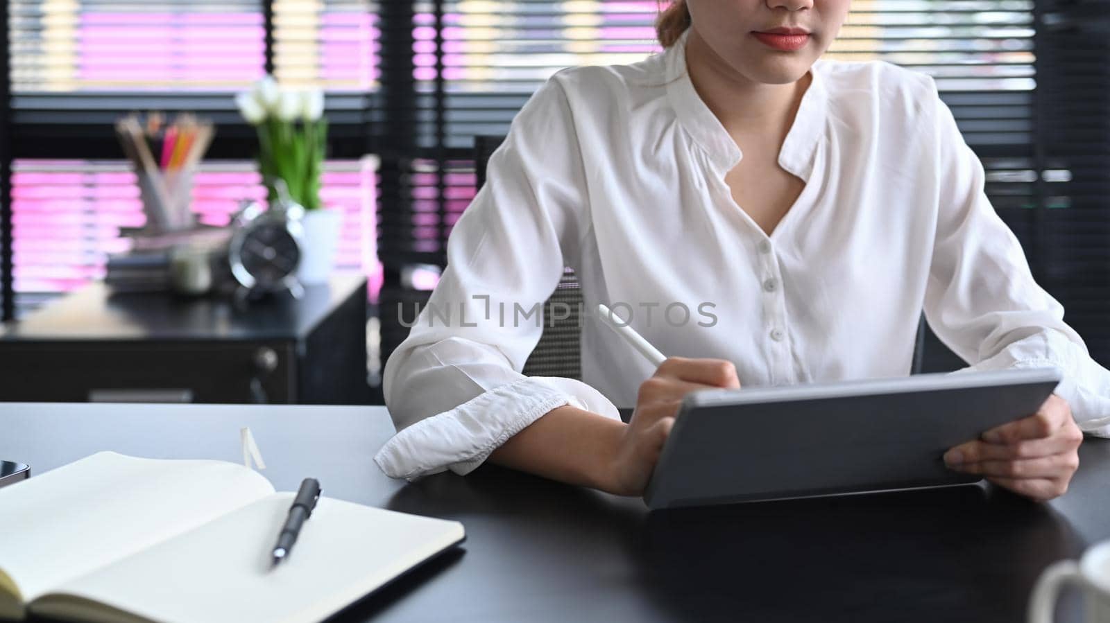 Cropped shot office worker using digital tablet at office desk.