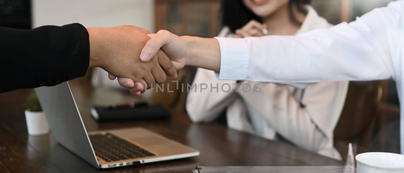 Business people shaking hands, finishing up meeting or negotiation in office by prathanchorruangsak