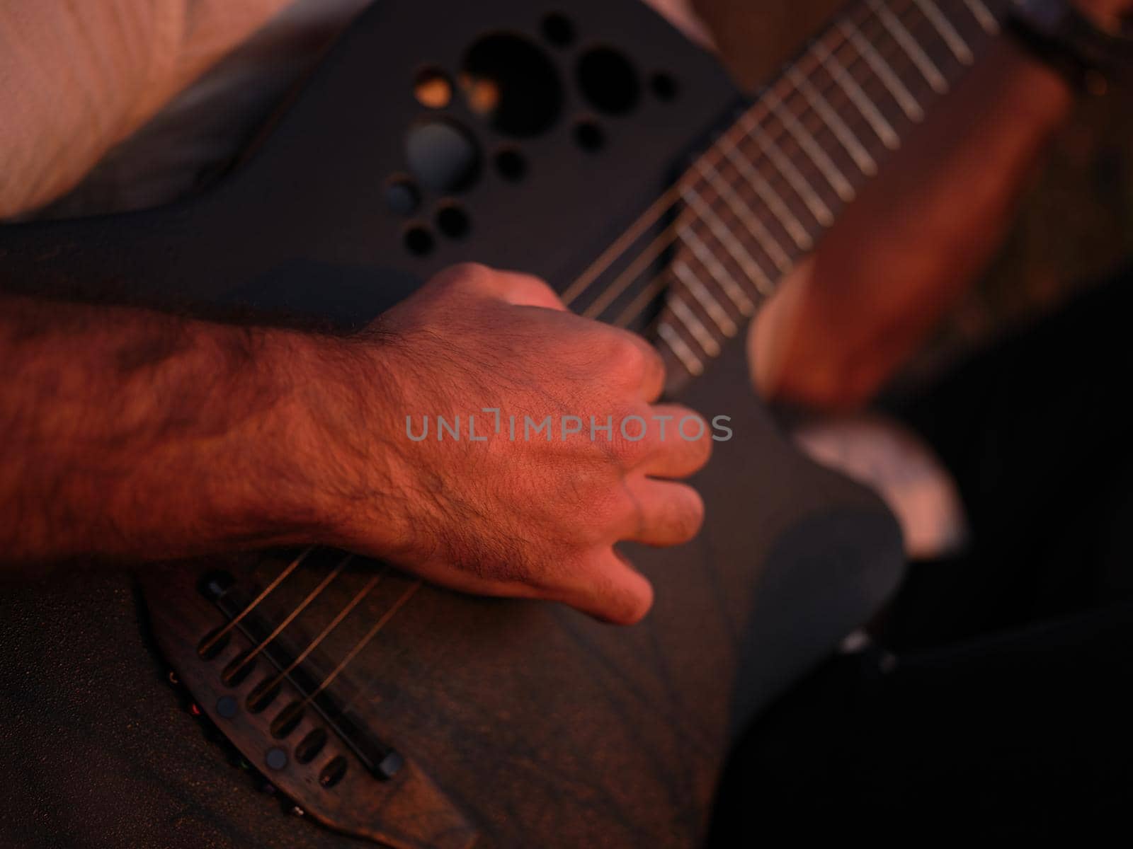 close-up view of a man playing the guitar in the sunlight, horizontal picture, blurred background