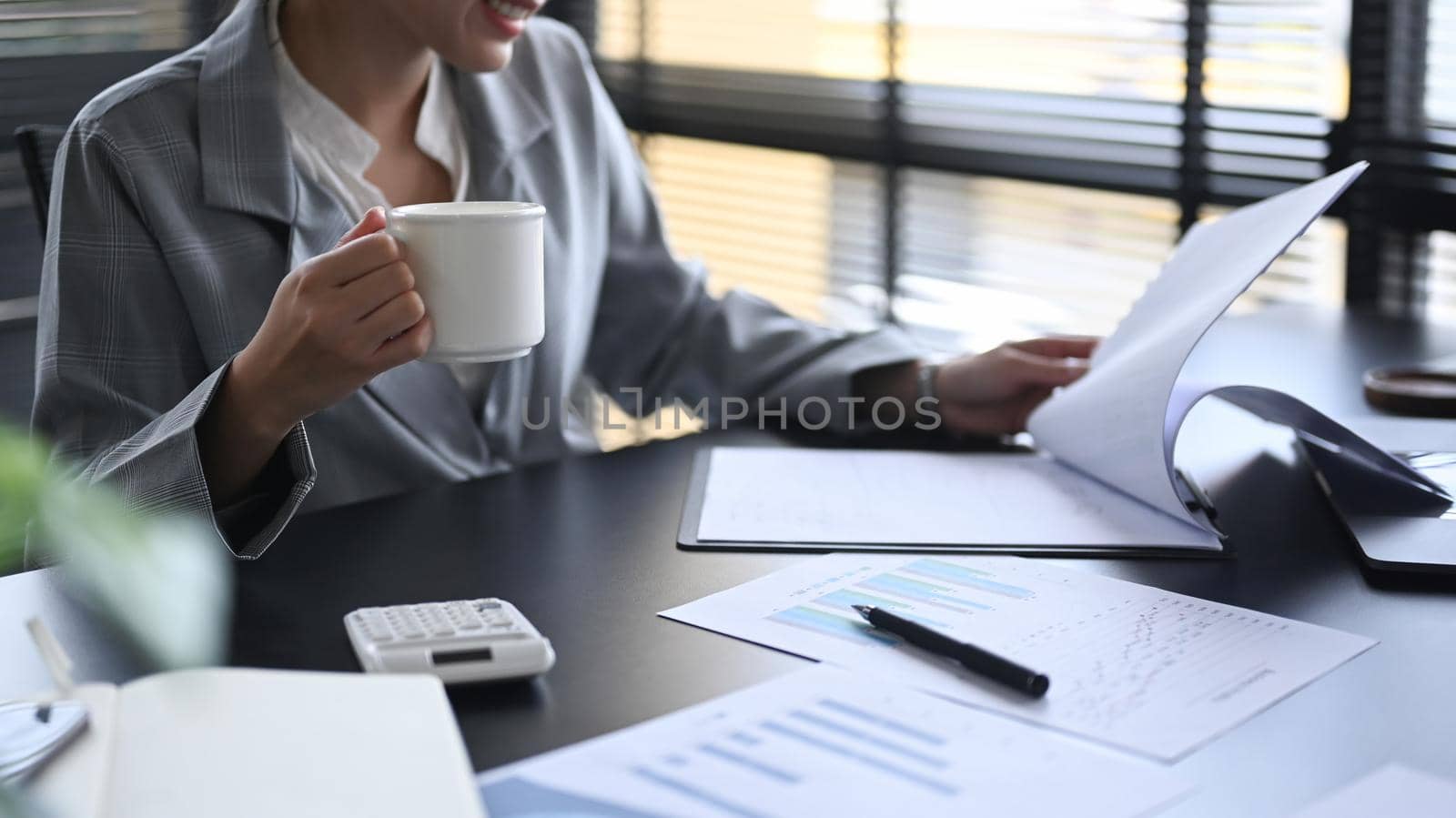 Female manager sitting in bright modern office and checking financial reports.