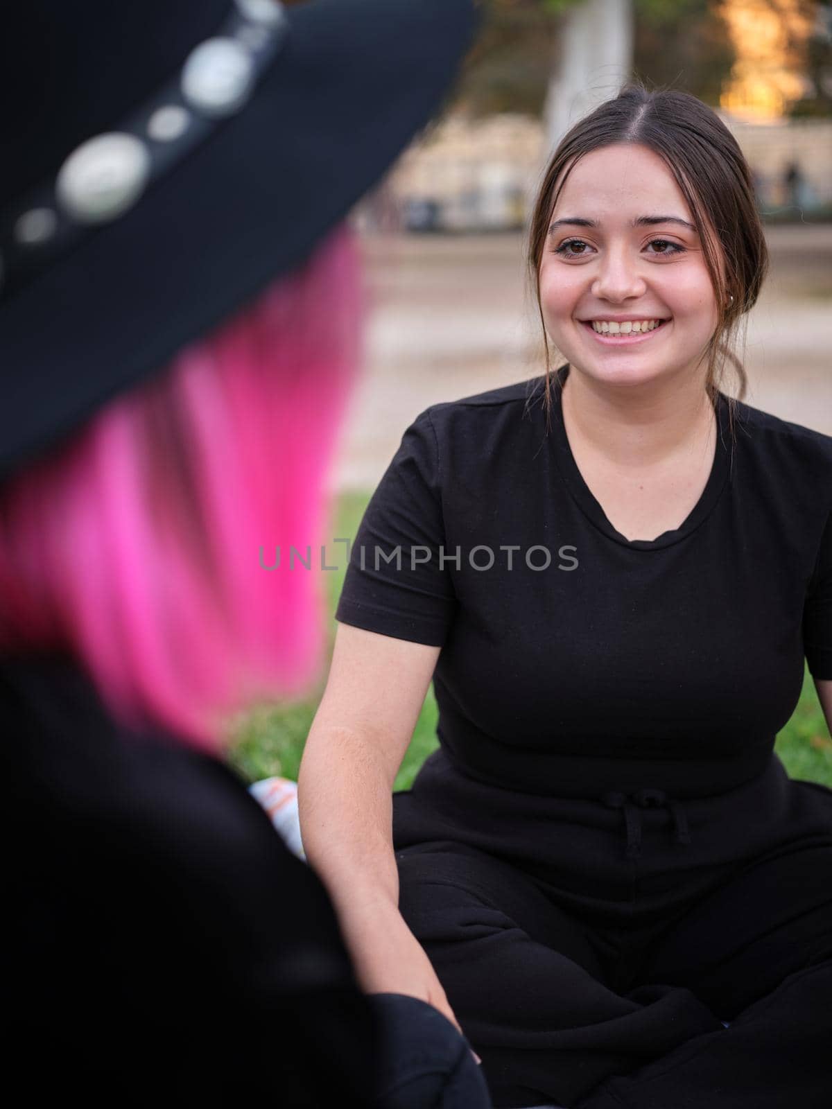 woman sitting smiling and looking at her friend, vertical image, frontal view
