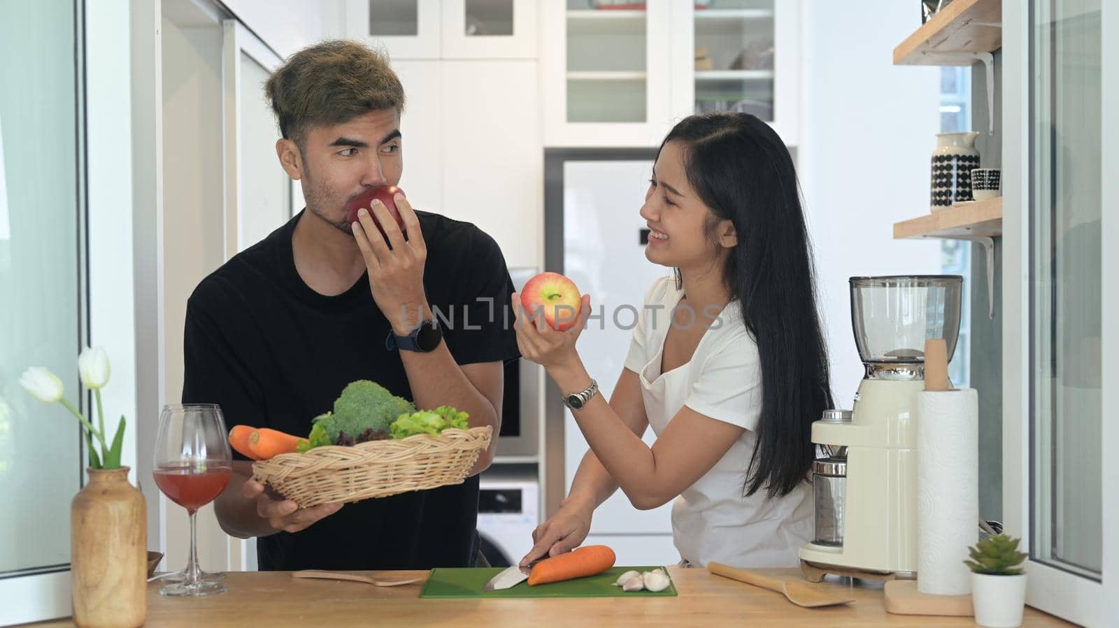 Healthy young couple enjoy making green detox smoothie with fresh vegetables and fruits in the kitchen.