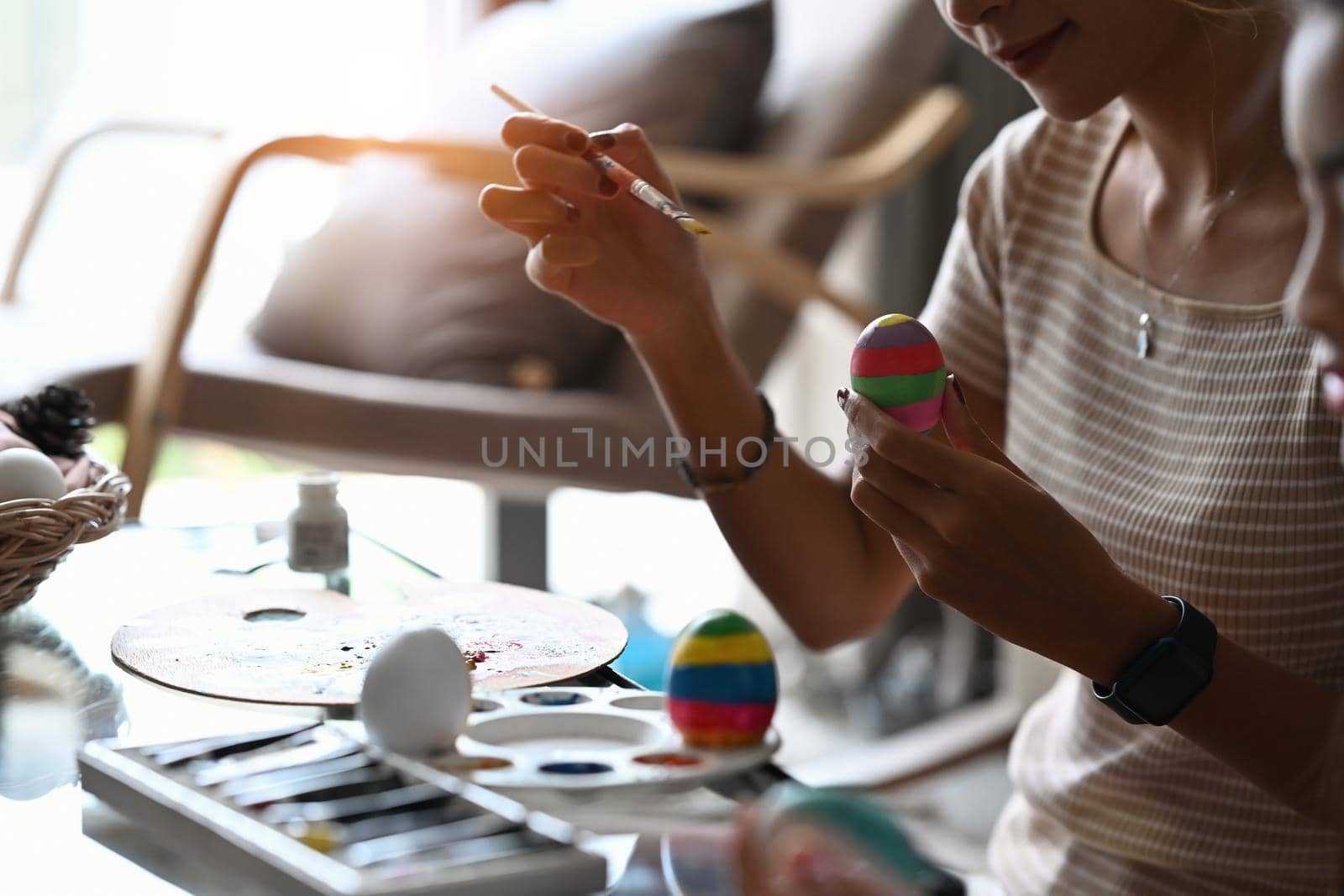 Female hand with paintbrush coloring egg for Easter. Happy Easter day.